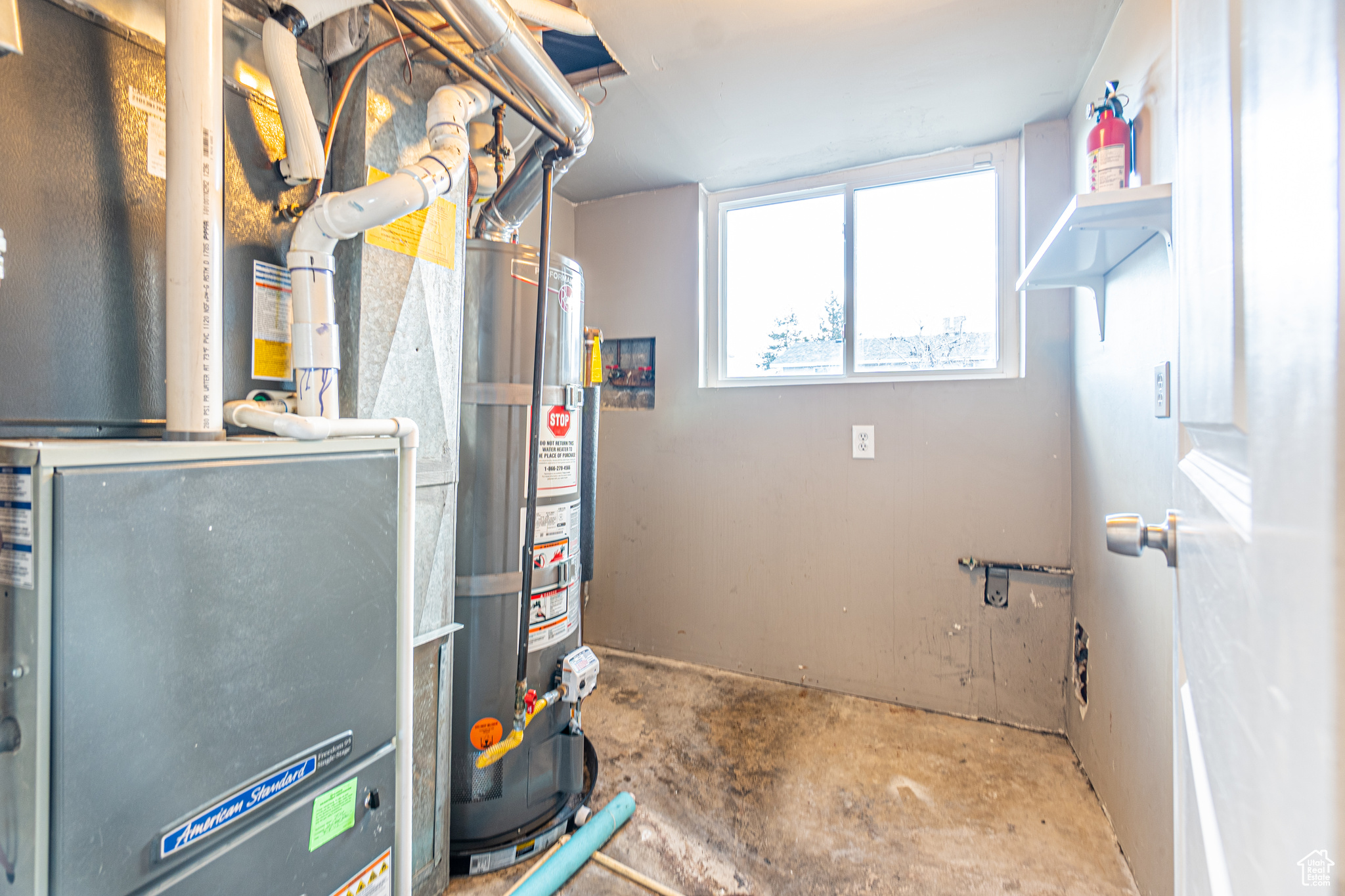 Utility room featuring gas water heater and heating unit, plus laundry hookups