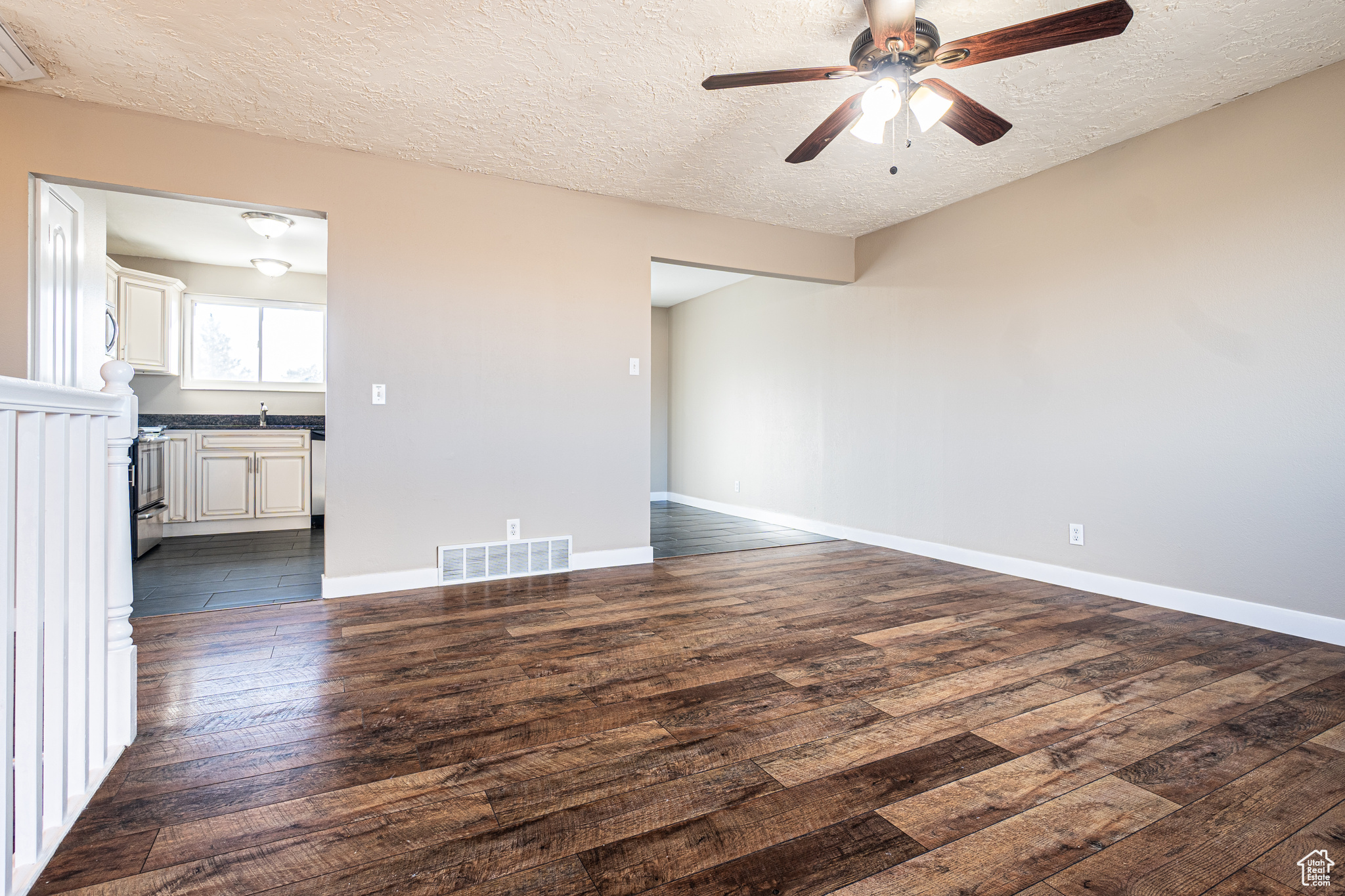 Unfurnished room featuring ceiling fan, sink, dark wood-type flooring, and a textured ceiling