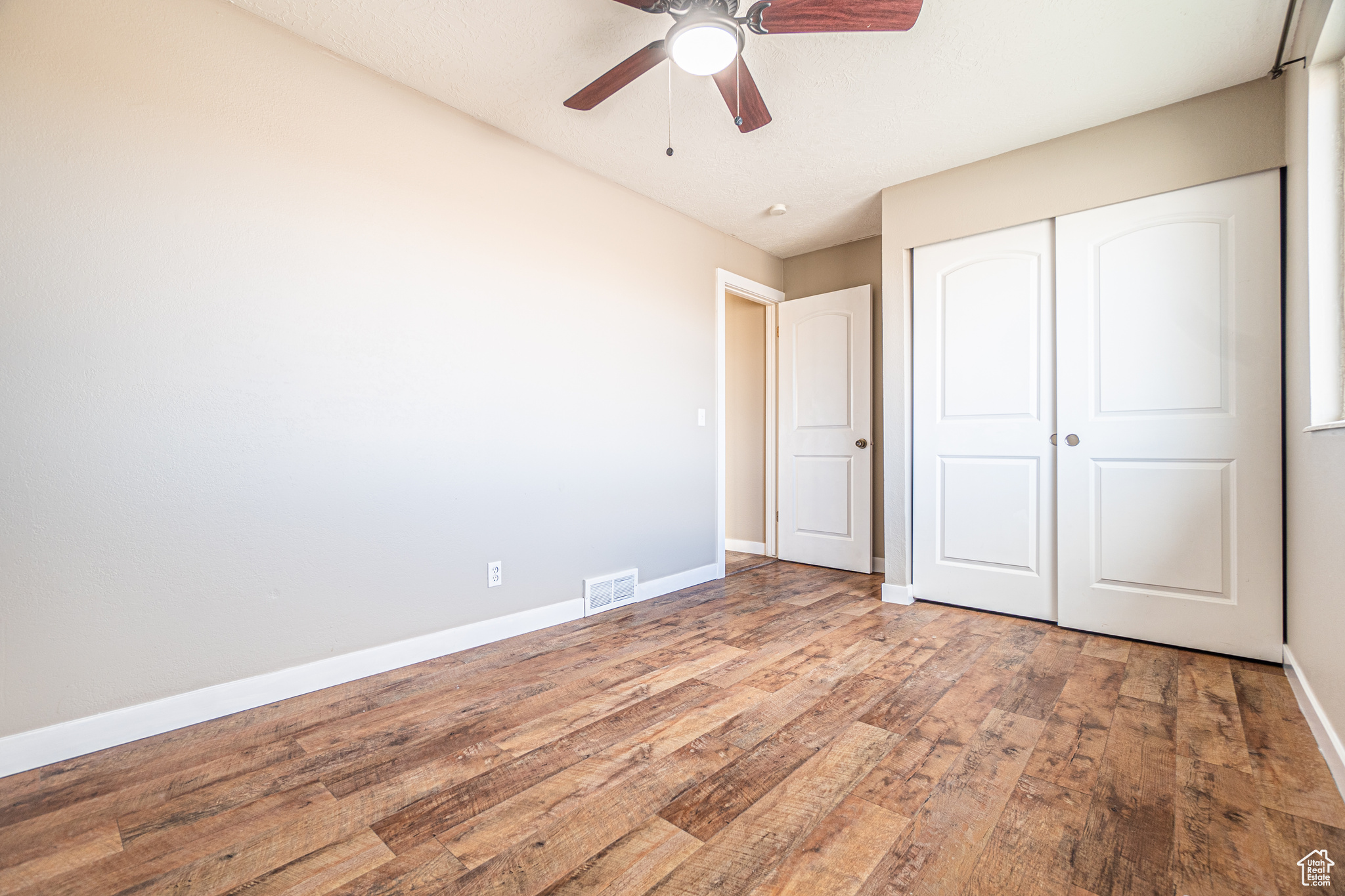 Unfurnished bedroom with ceiling fan, wood-type flooring, and a closet