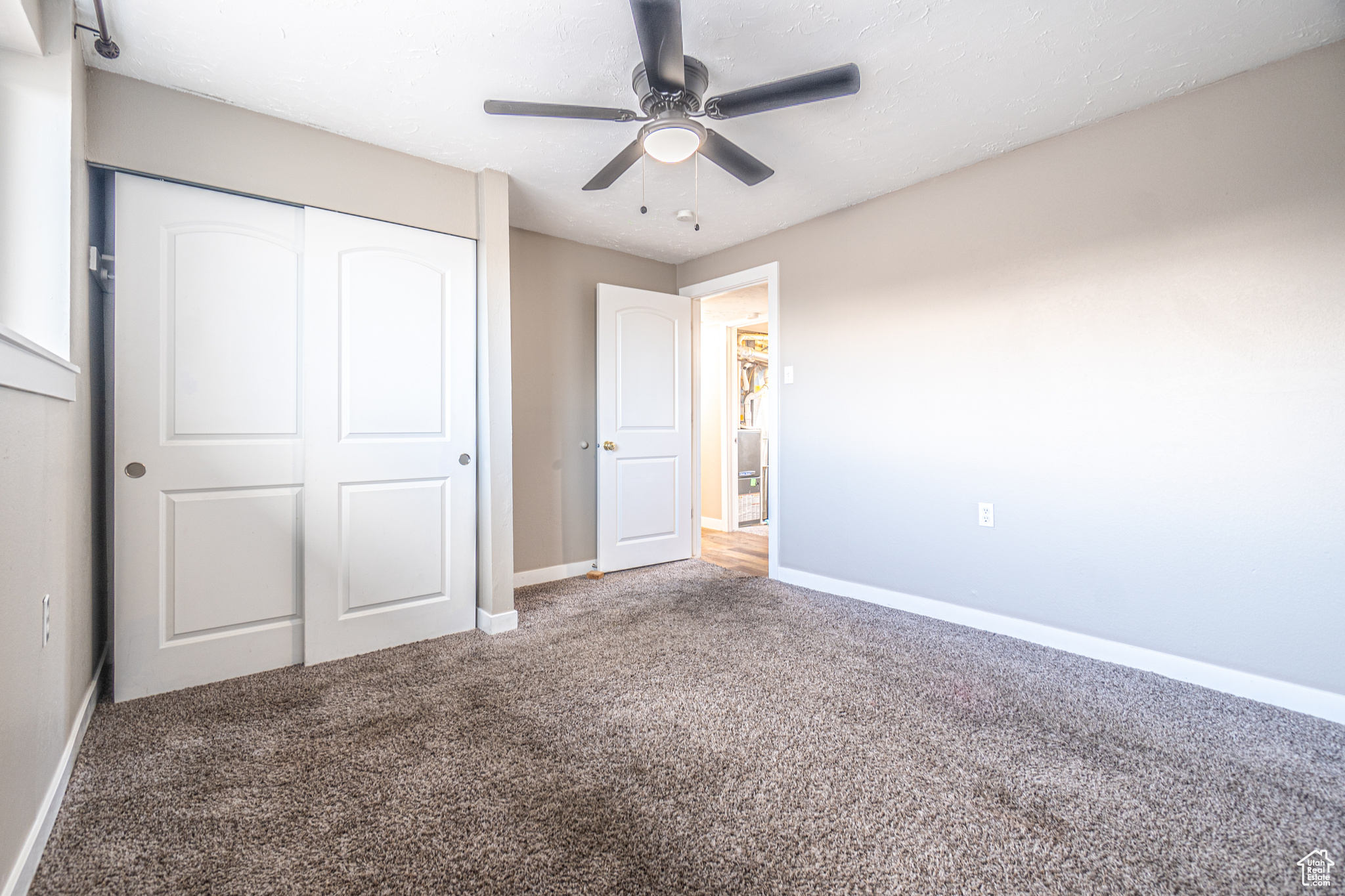 Unfurnished bedroom featuring carpet, a closet, and ceiling fan