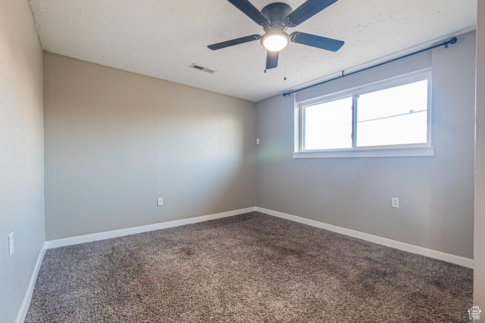 Empty room with ceiling fan and carpet floors