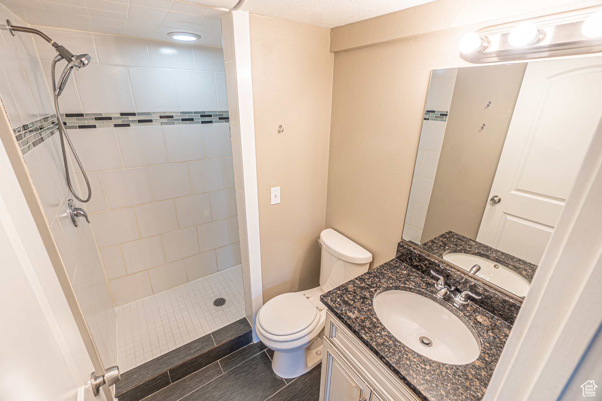 Bathroom with tiled shower, vanity, and toilet