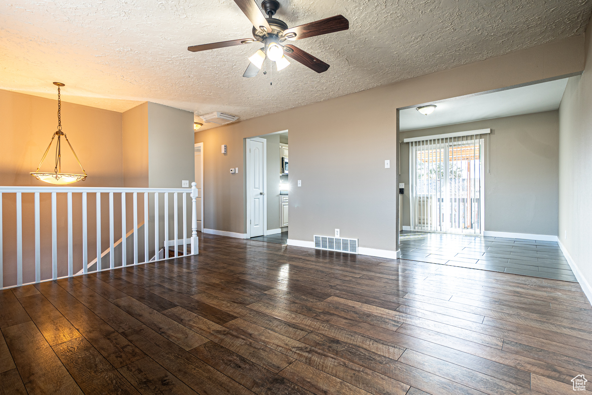 Empty room featuring a textured ceiling, dark hardwood / wood-style floors, and ceiling fan