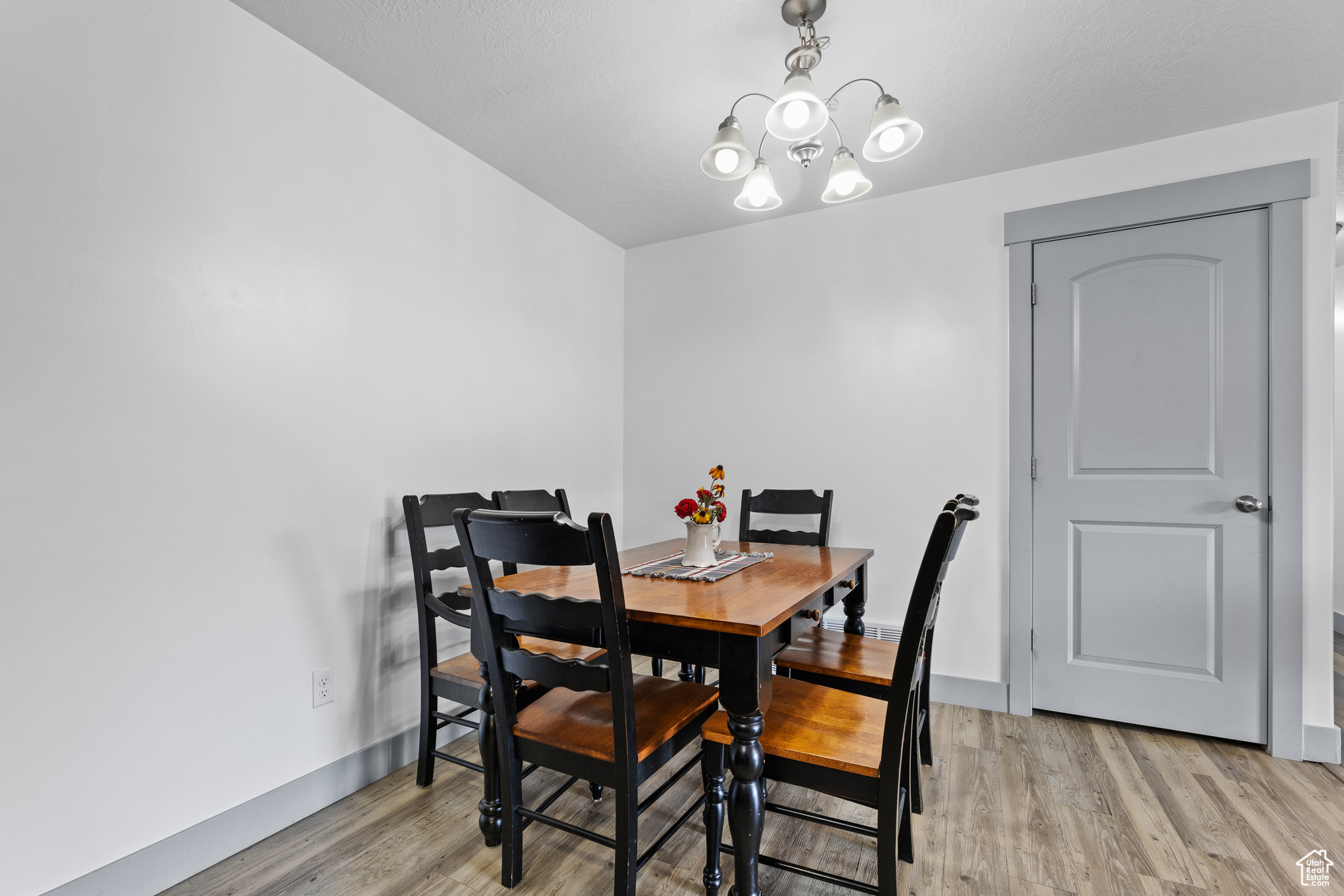 Dining room with light wood-type flooring and a notable chandelier