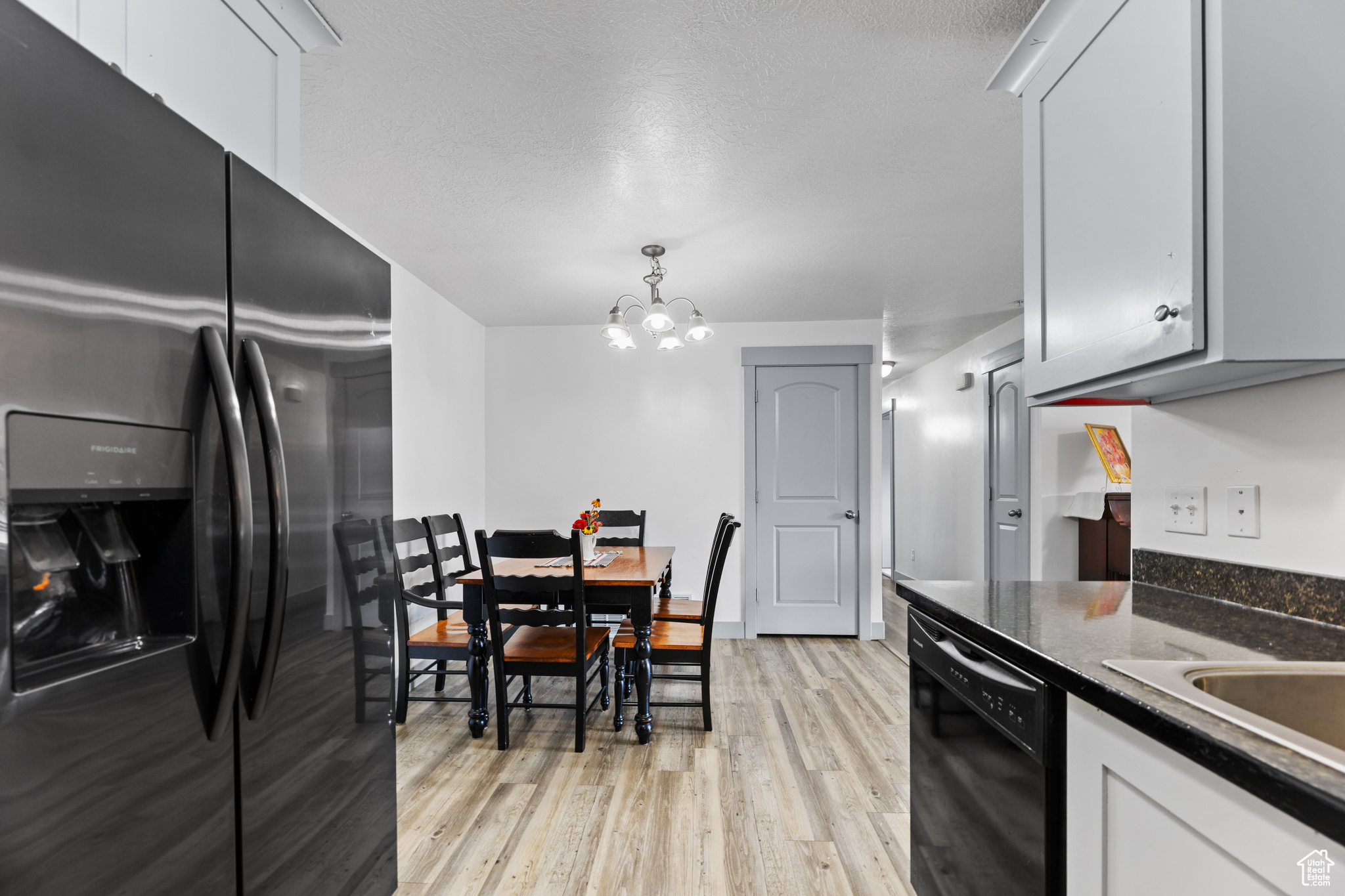 Kitchen with white cabinets, pendant lighting, a chandelier, and black appliances