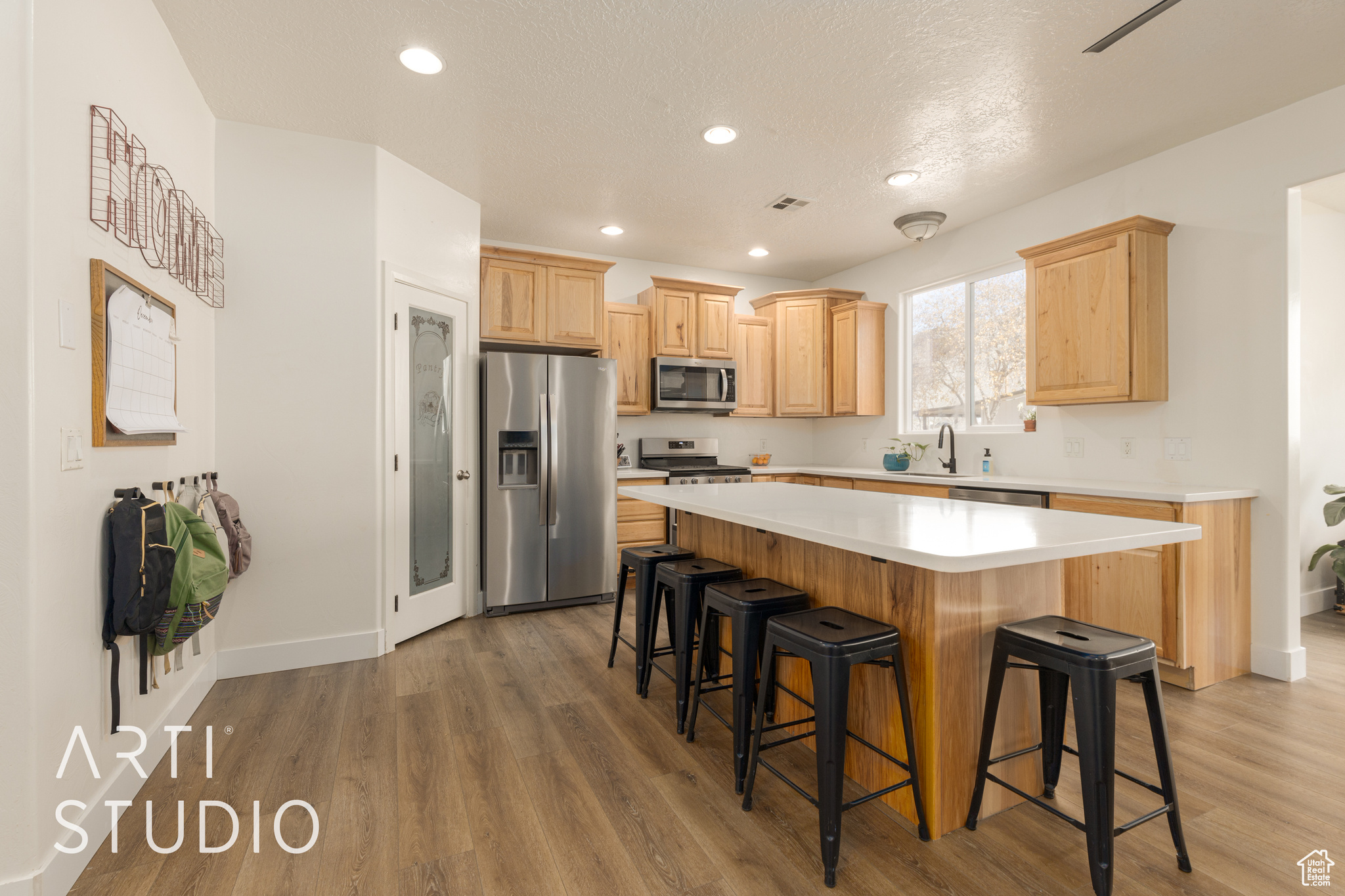 Kitchen featuring stainless steel appliances, sink, light brown cabinets, hardwood / wood-style flooring, and a center island