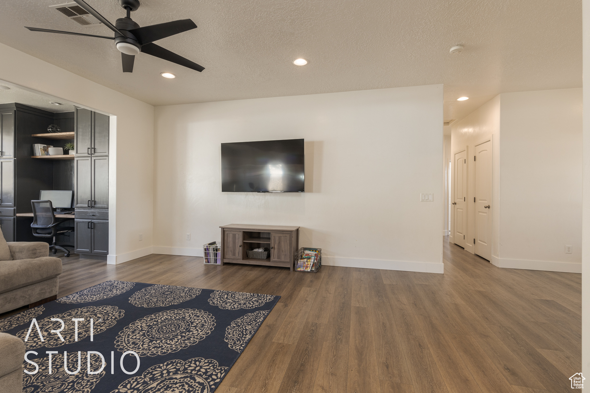 Living room featuring ceiling fan, dark wood-type flooring, and a textured ceiling