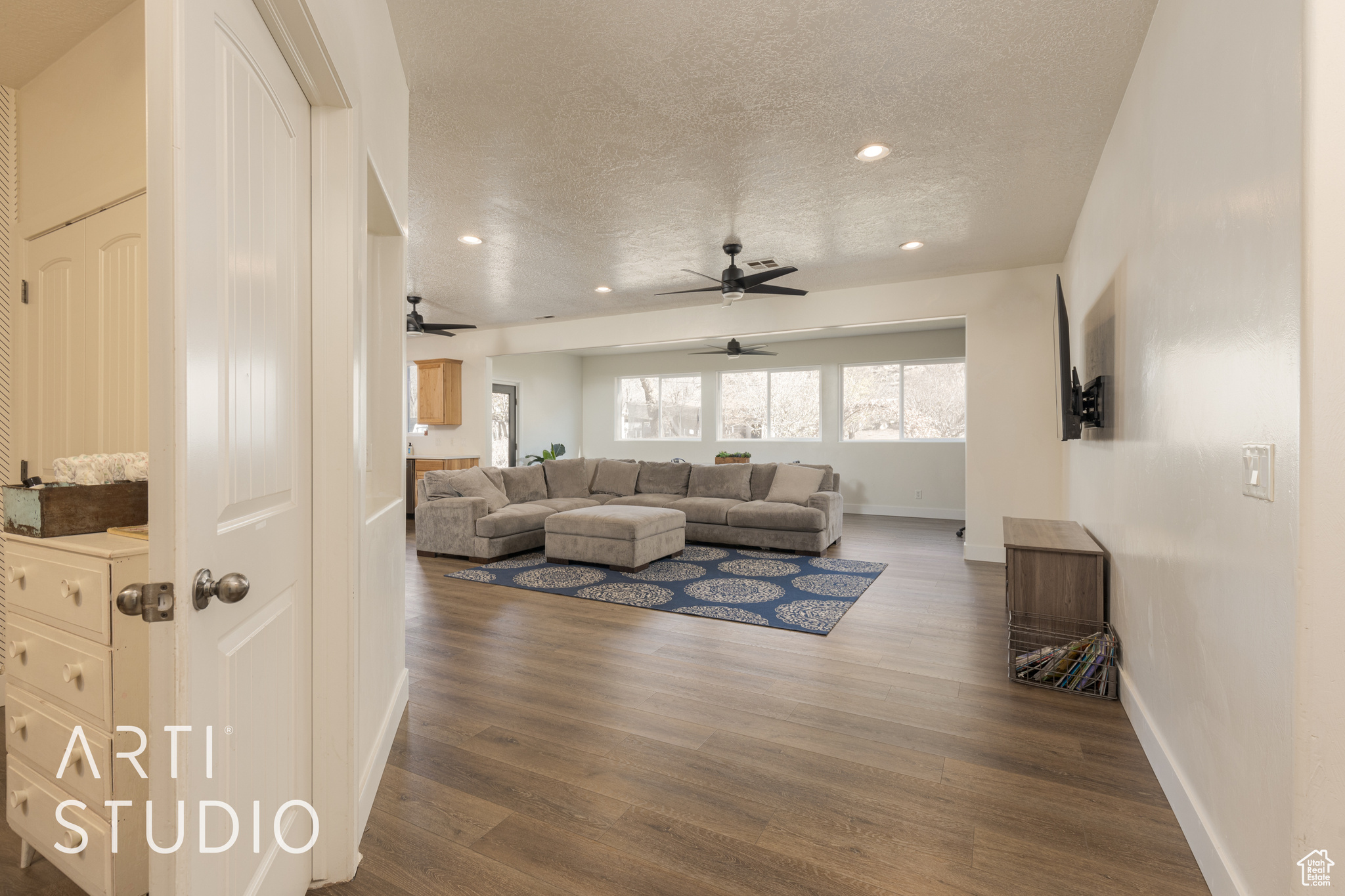 Living room with a textured ceiling, ceiling fan, and dark hardwood / wood-style floors