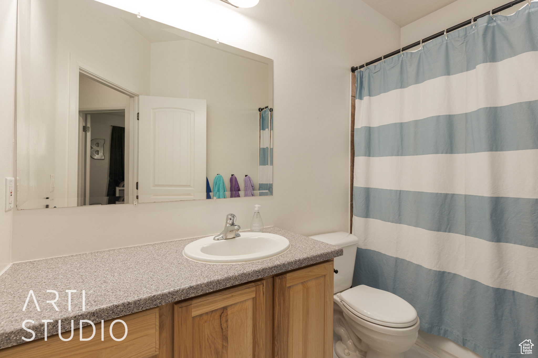 Bathroom featuring a shower with shower curtain, vanity, and toilet