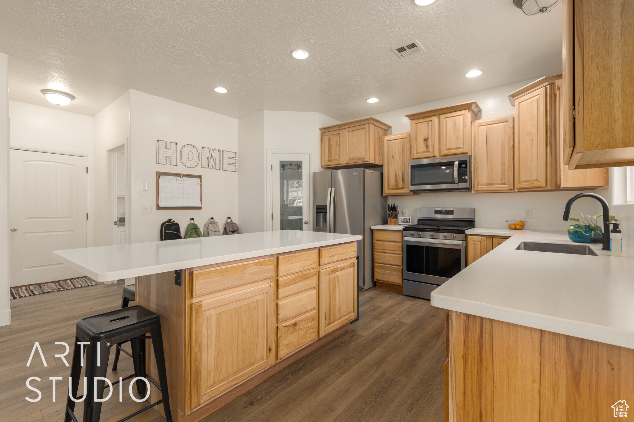 Kitchen with a center island, dark wood-type flooring, a kitchen breakfast bar, sink, and appliances with stainless steel finishes