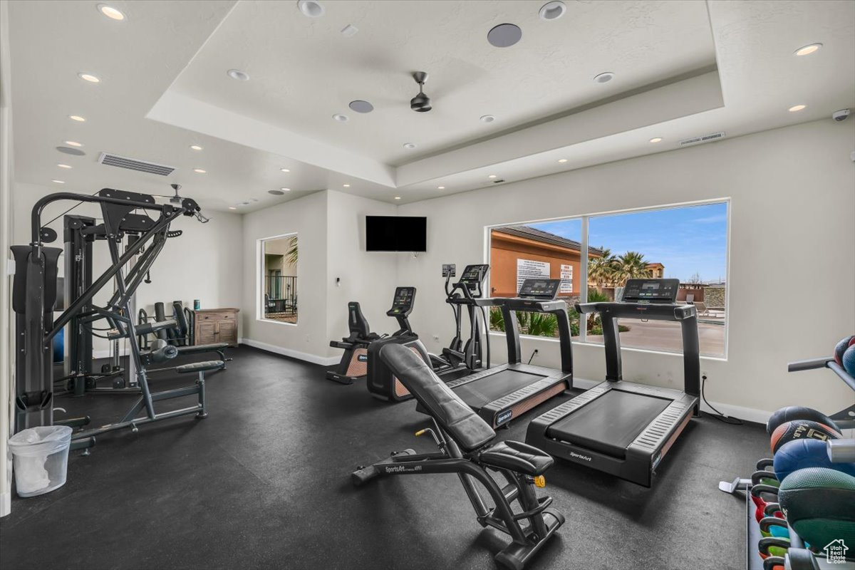 Workout area with ceiling fan and a raised ceiling