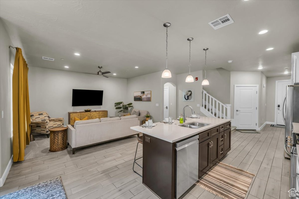 Kitchen featuring dishwasher, a kitchen island with sink, sink, ceiling fan, and dark brown cabinets