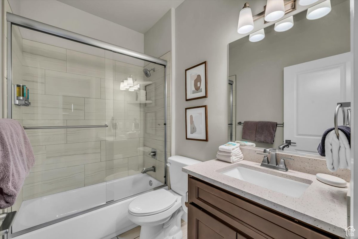 Full bathroom with toilet, combined bath / shower with glass door, and vanity