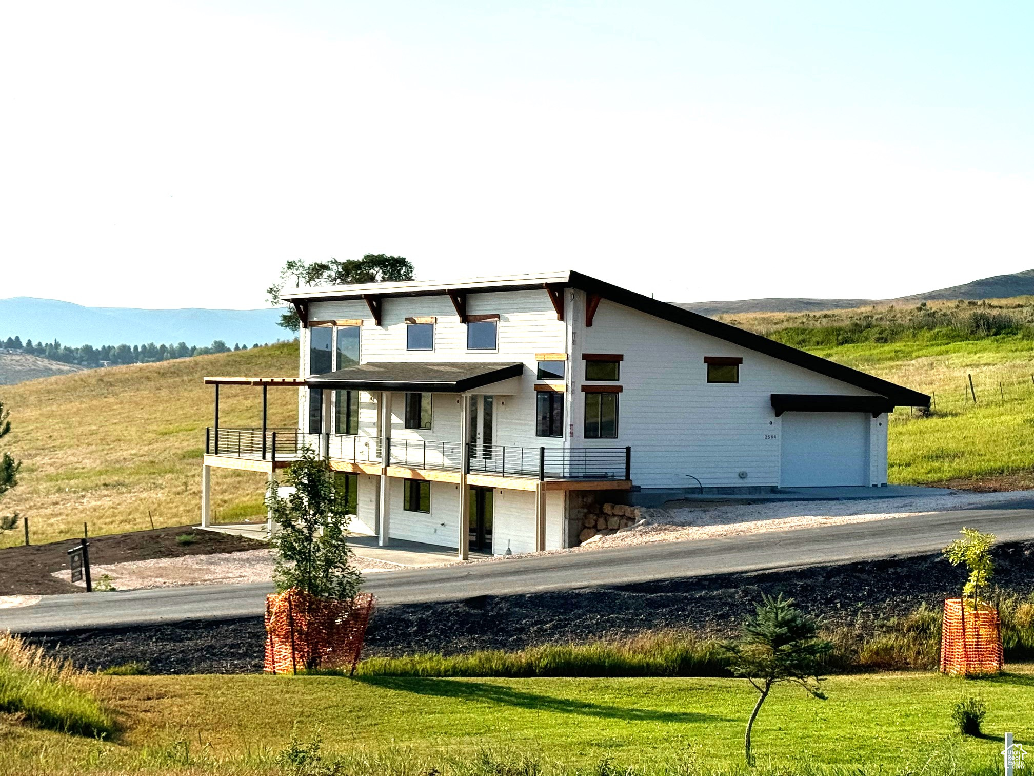 Back of house featuring a lawn, a mountain view, and a balcony