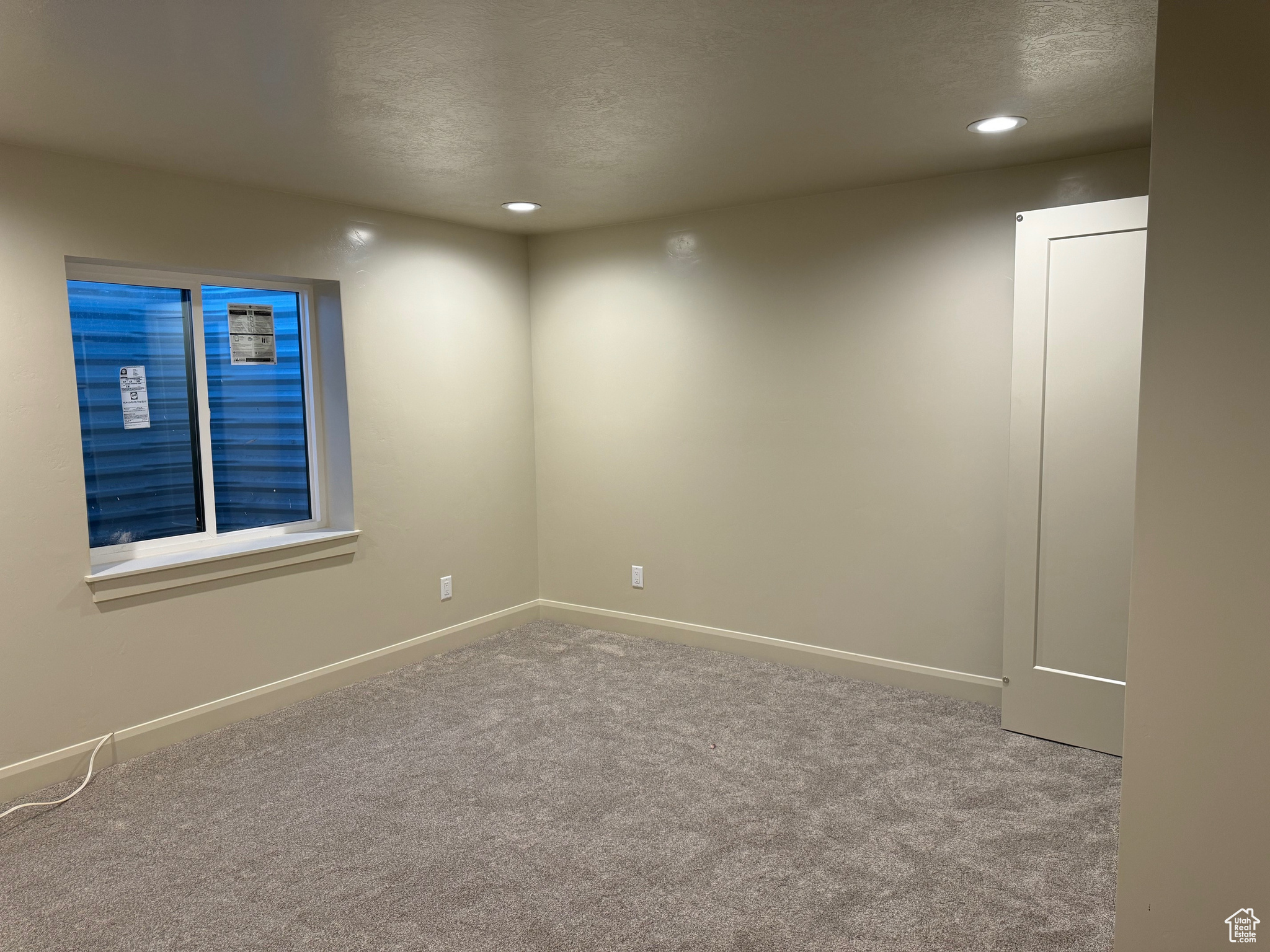 Unfurnished room featuring light colored carpet and a textured ceiling