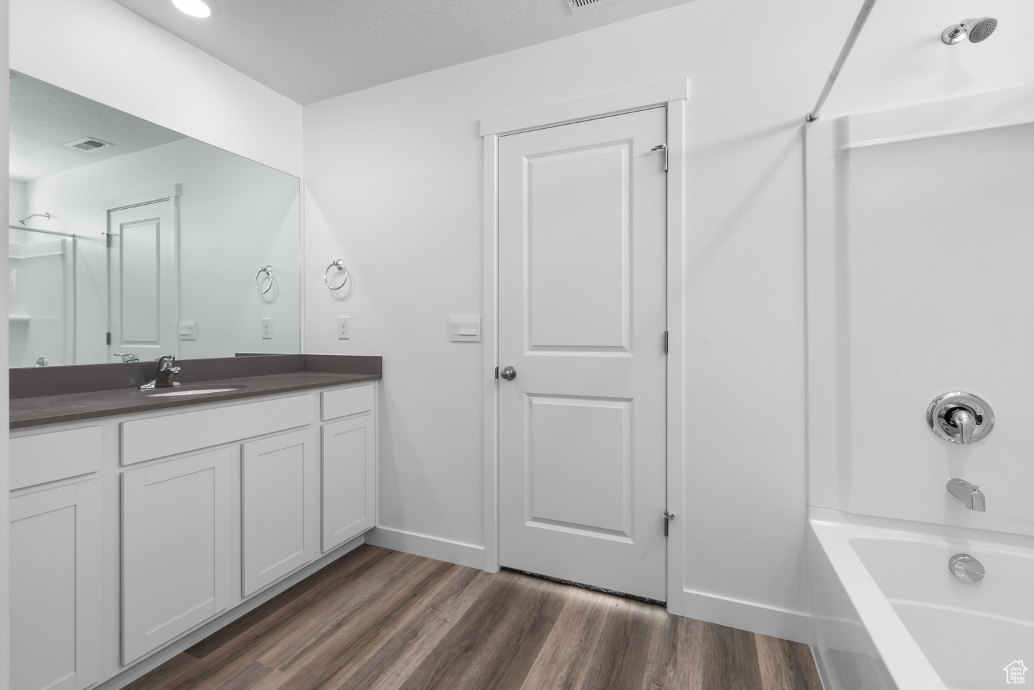 Bathroom featuring hardwood / wood-style floors, vanity, and shower / bathing tub combination