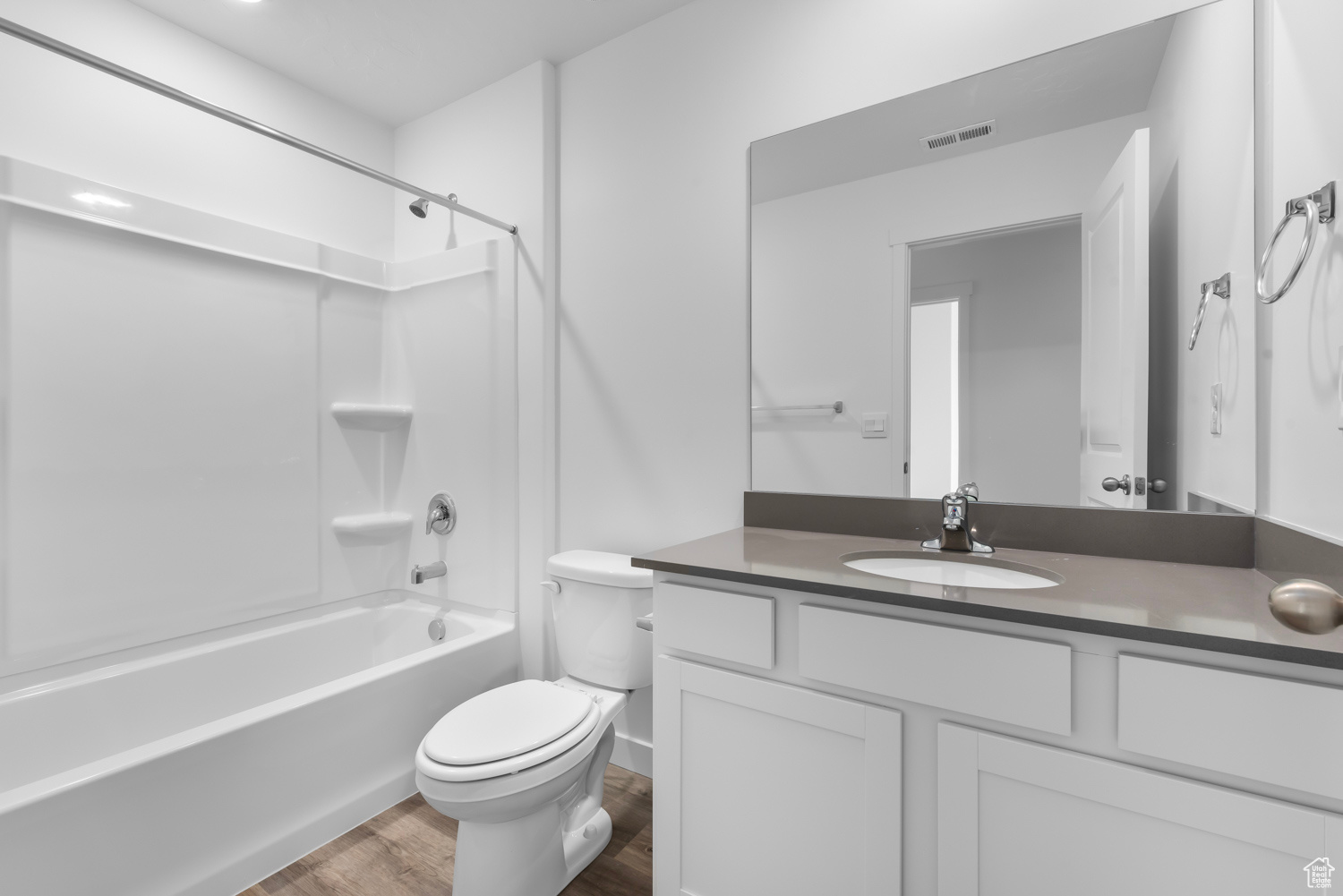 Full bathroom with toilet, vanity, bathtub / shower combination, and hardwood / wood-style flooring