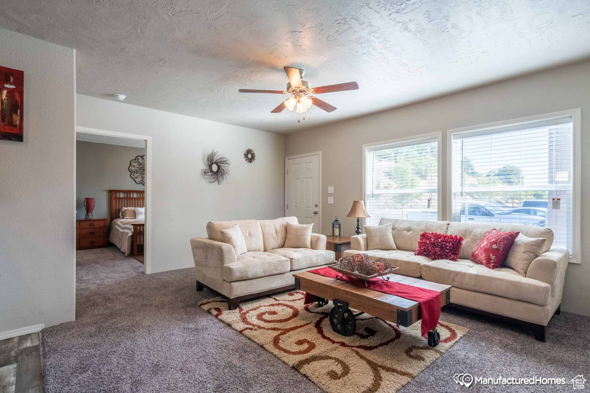 Carpeted living room with a textured ceiling and ceiling fan