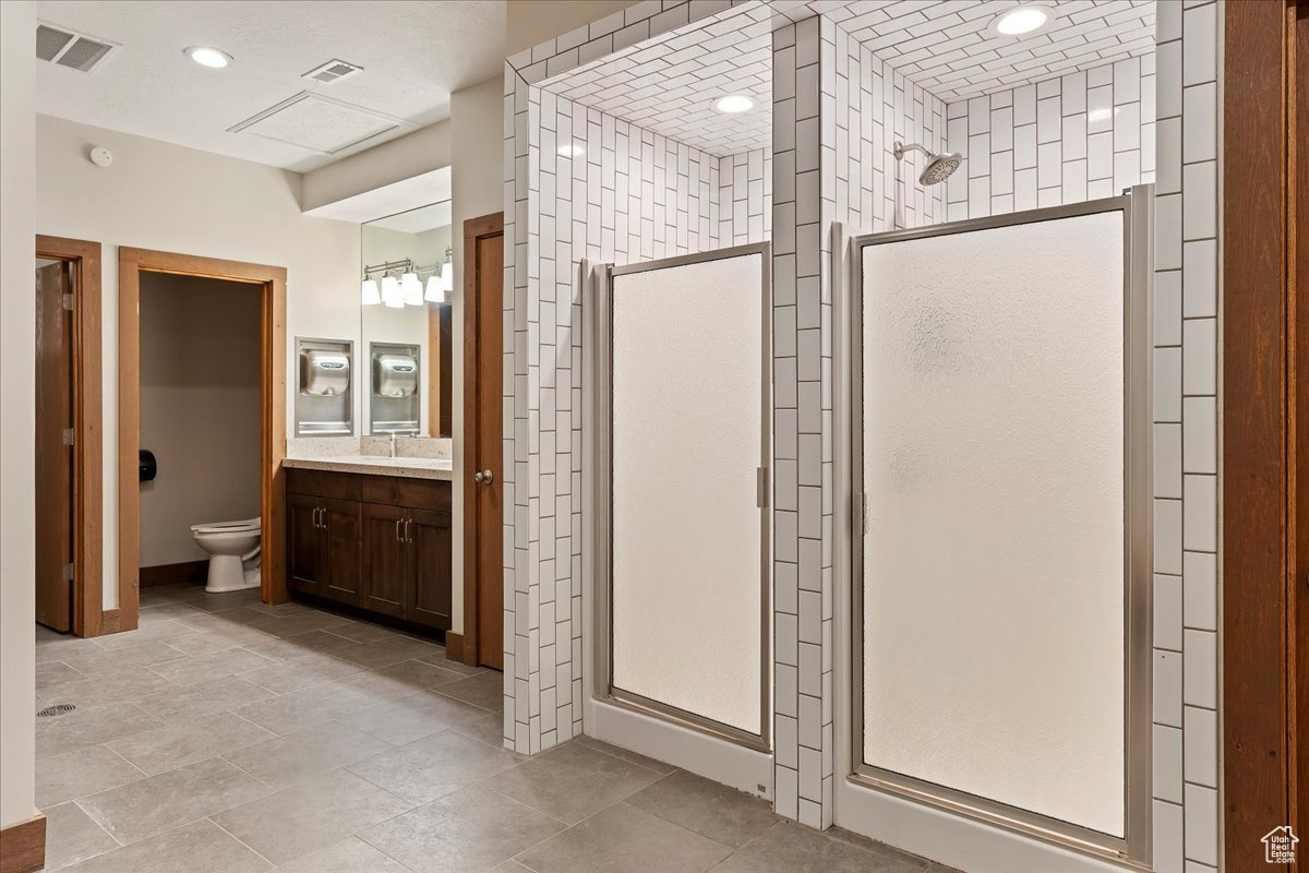 Bathroom featuring vanity, a shower with shower door, and toilet