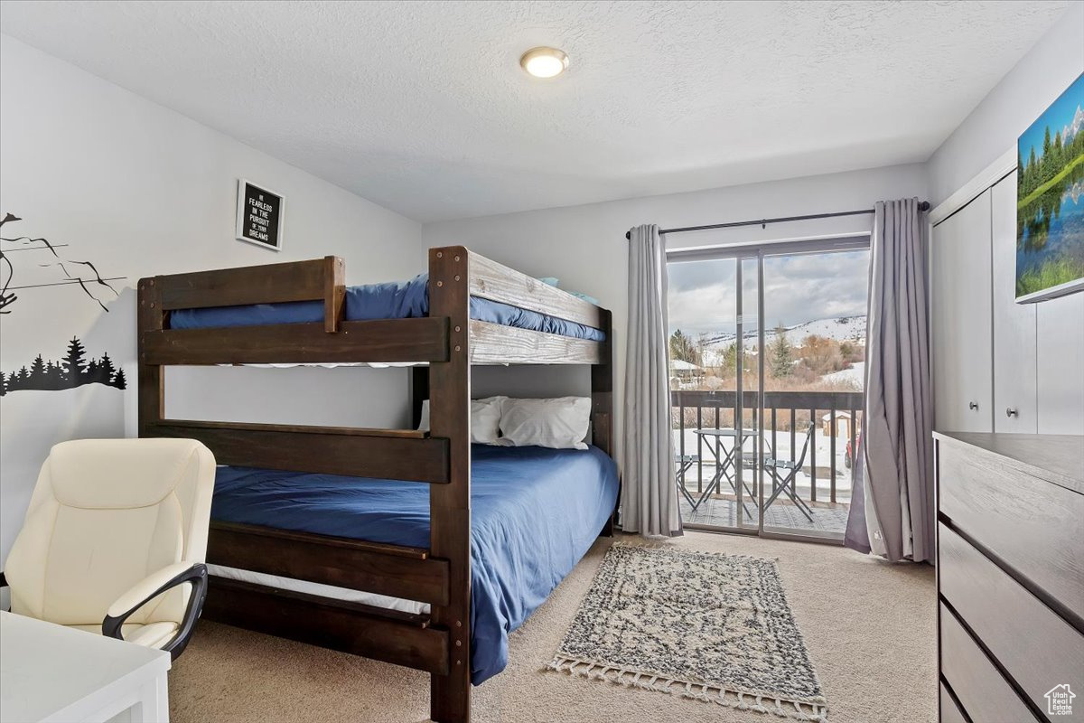 Carpeted bedroom with access to exterior, a textured ceiling, and a closet