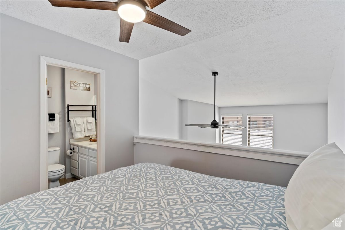 Bedroom featuring a textured ceiling, ensuite bath, and ceiling fan