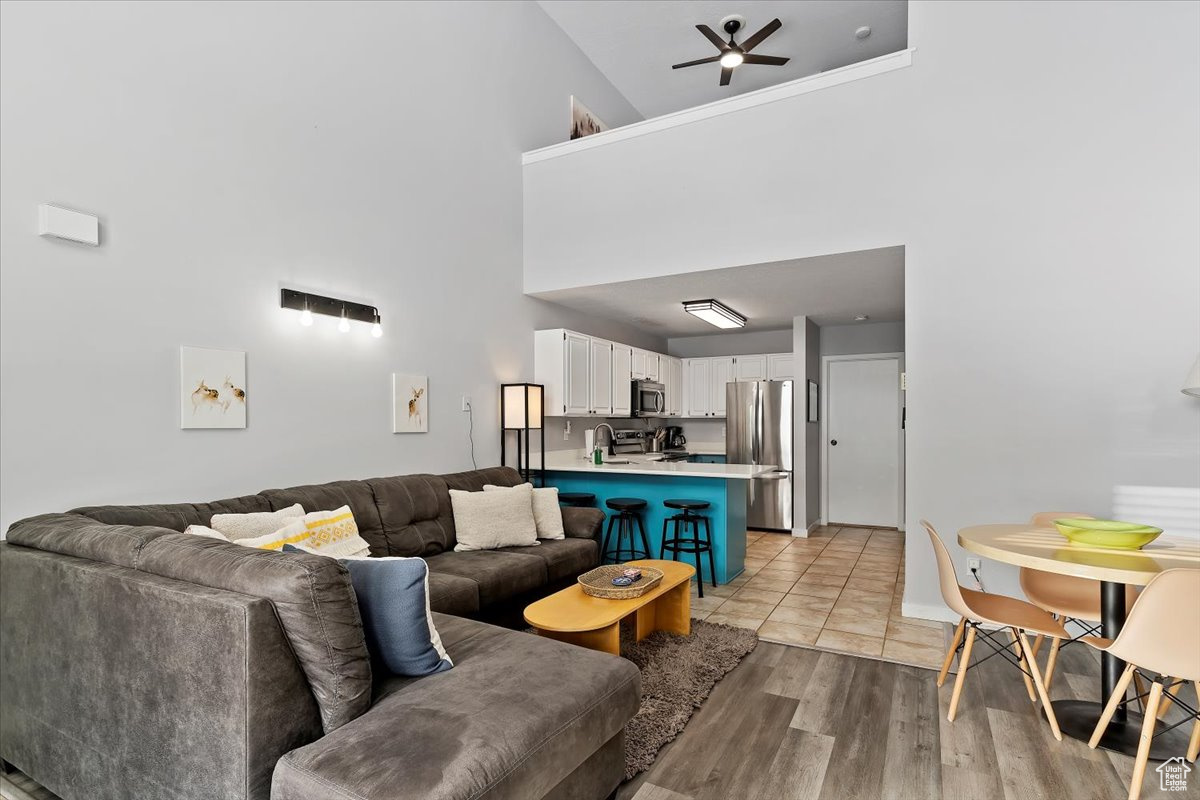 Living room featuring ceiling fan, light hardwood / wood-style floors, and a high ceiling