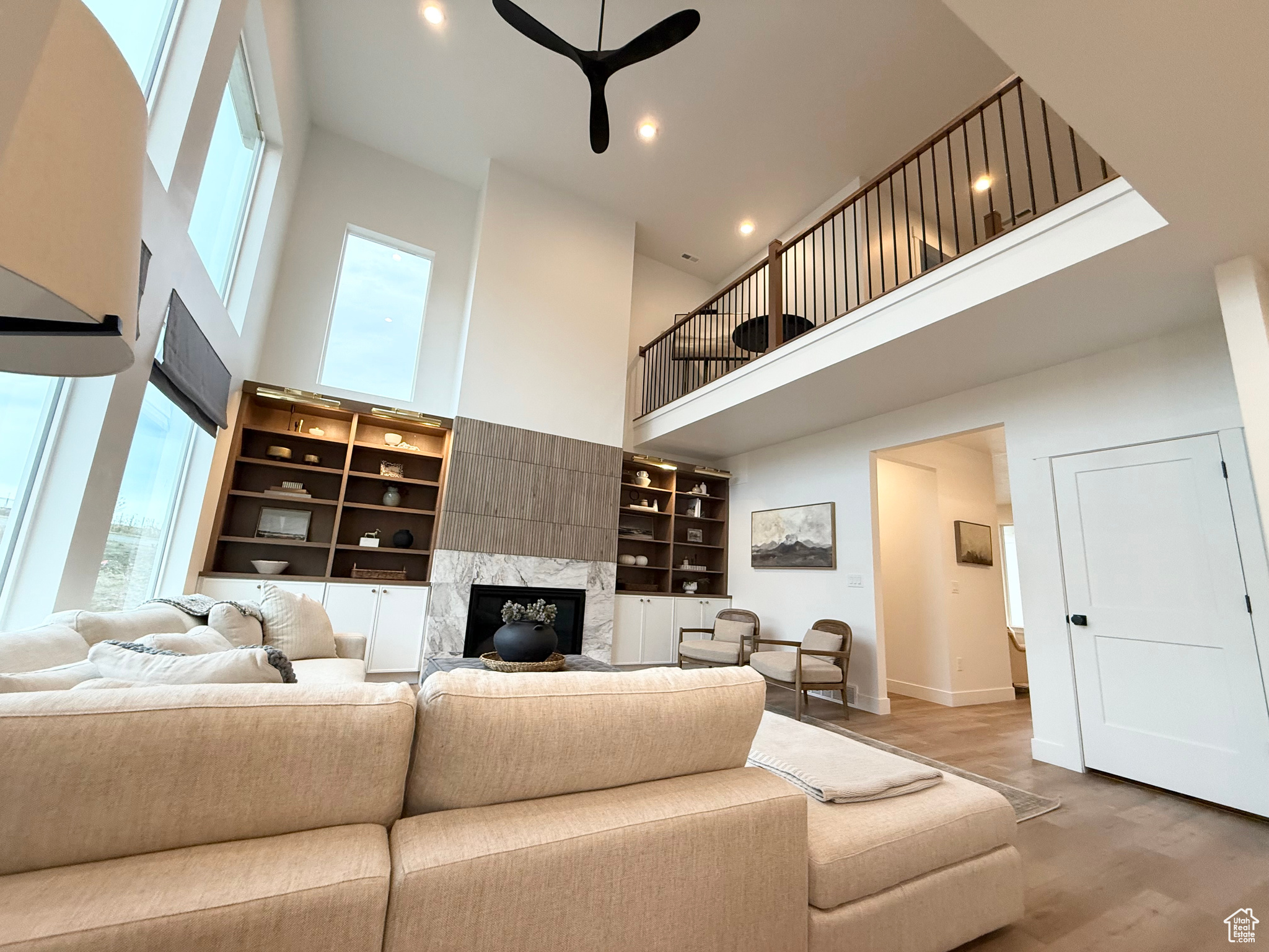 Living room featuring hardwood / wood-style flooring, ceiling fan, a towering ceiling, and a premium fireplace