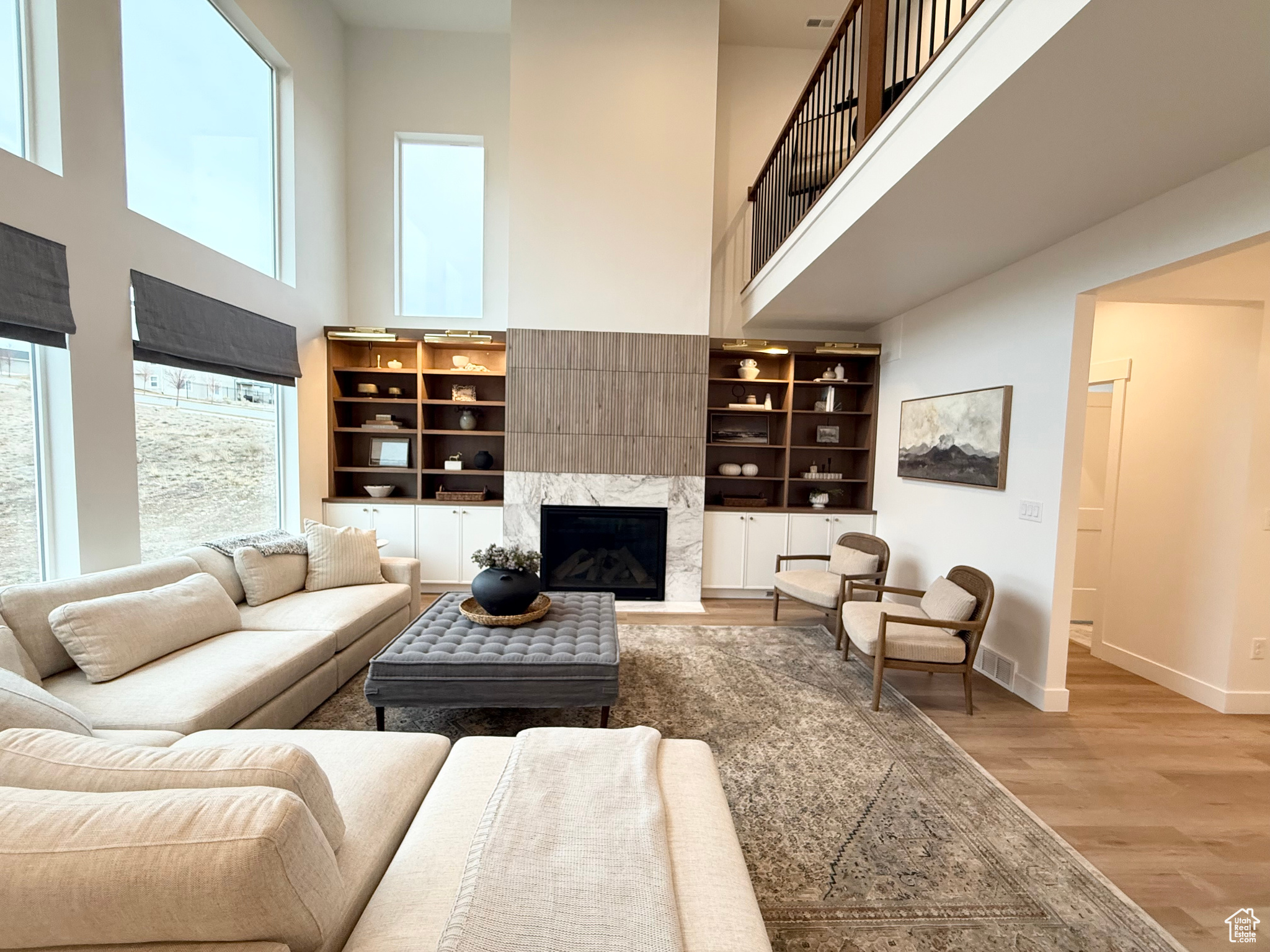 Living room featuring a towering ceiling, light hardwood / wood-style floors, a wealth of natural light, and a premium fireplace