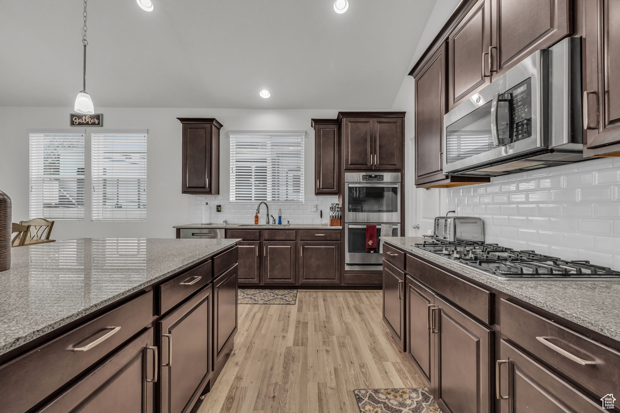 Kitchen with double ovens, decorative light fixtures, stainless steel appliances, and backsplash