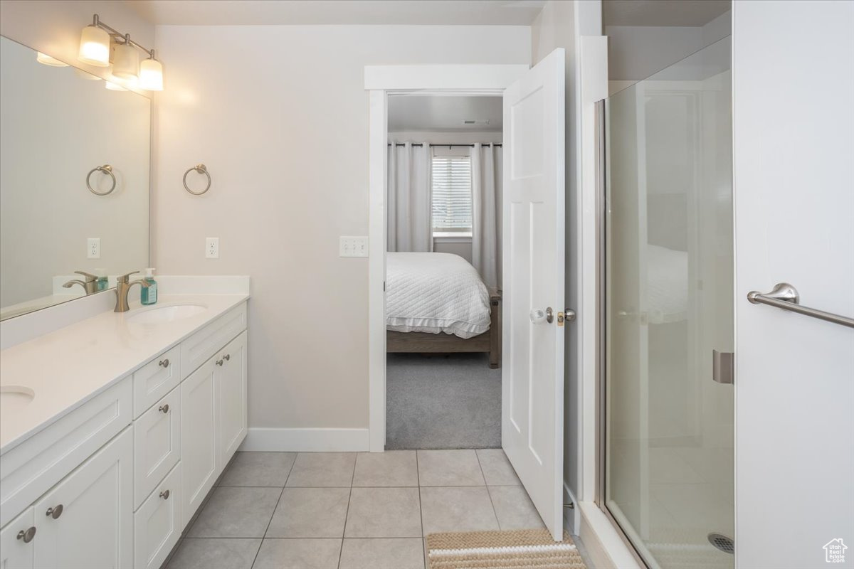 Bathroom featuring tile patterned flooring, vanity, and an enclosed shower