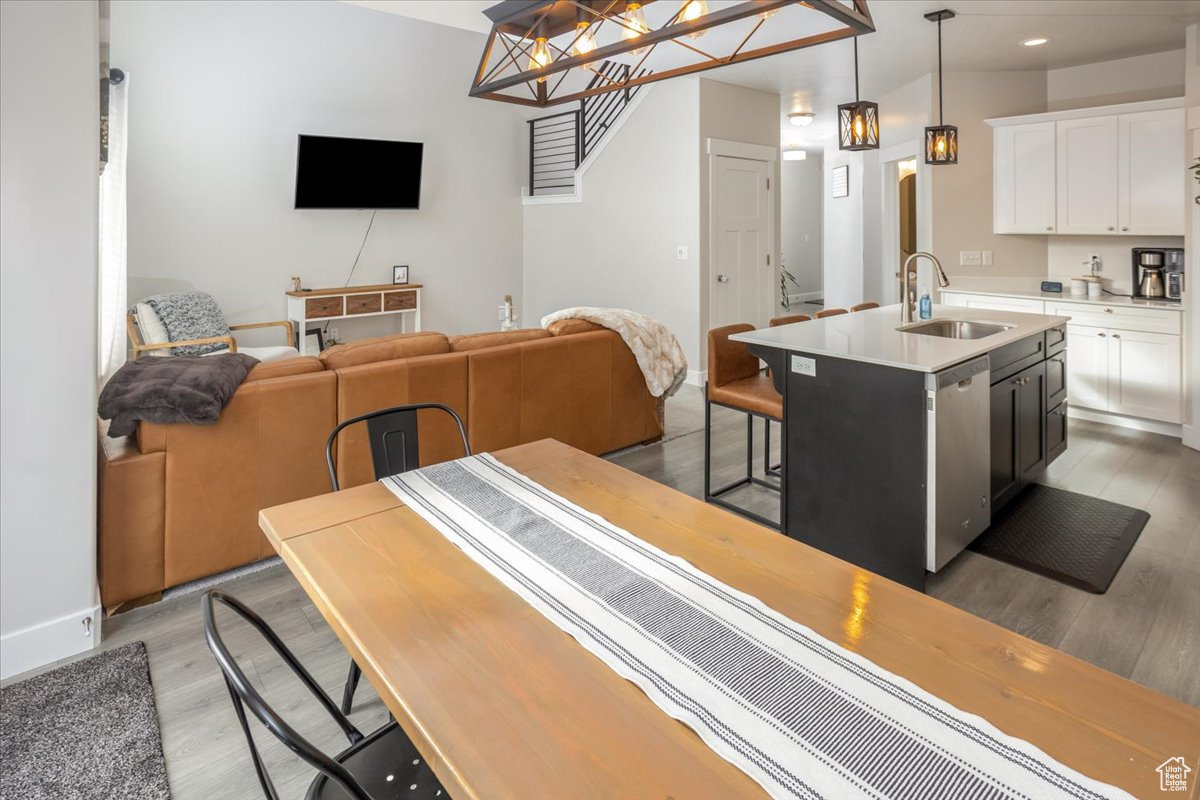 Kitchen featuring white cabinetry, a center island with sink, pendant lighting, and light wood-type flooring