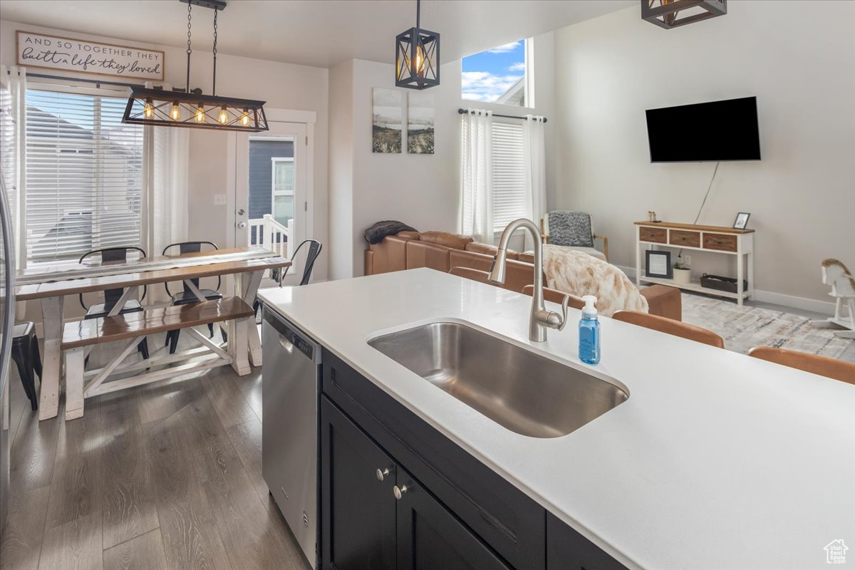 Kitchen with dishwasher, pendant lighting, dark hardwood / wood-style floors, and sink