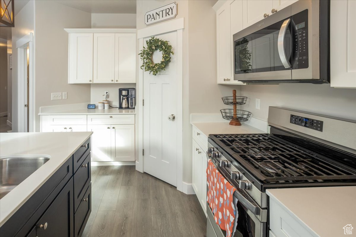 Kitchen featuring sink, white cabinets, stainless steel appliances, and hardwood / wood-style flooring