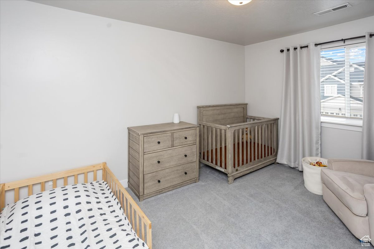 Bedroom featuring light colored carpet, multiple windows, and a nursery area