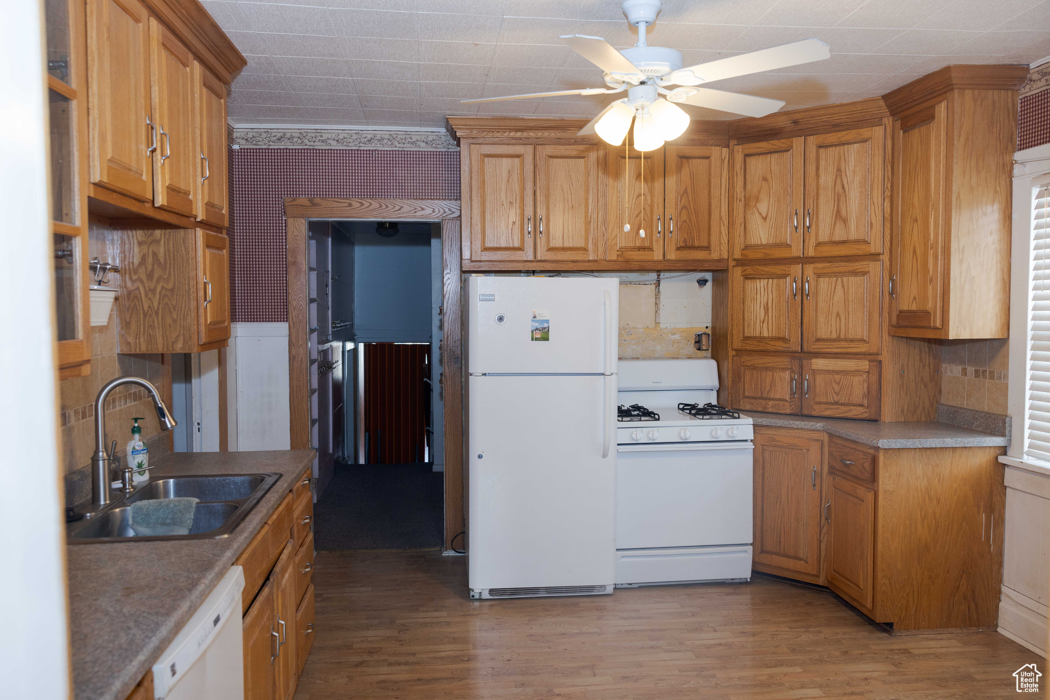 Kitchen featuring white appliances, light hardwood / wood-style flooring, ceiling fan, and sink