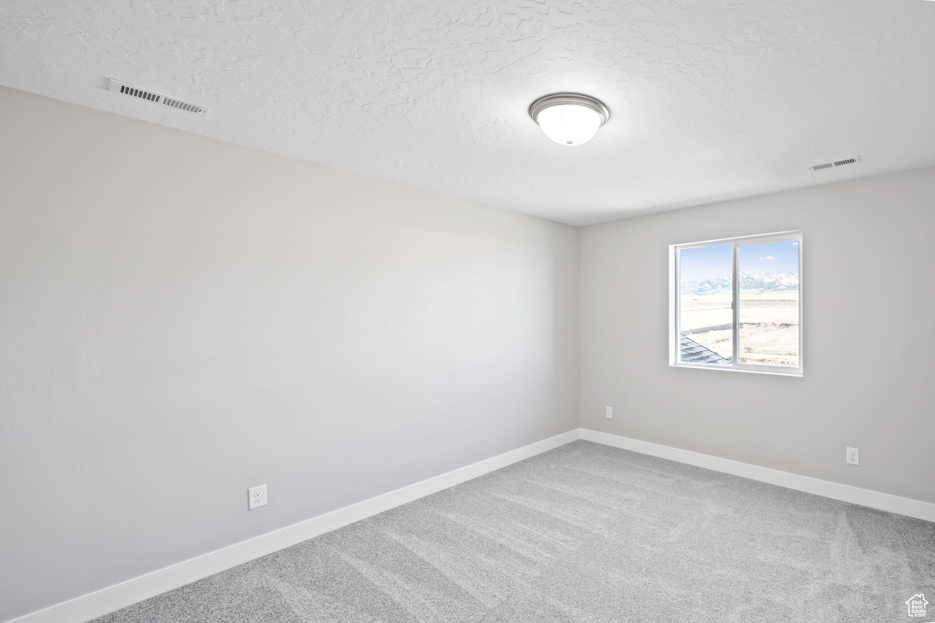 Empty room with carpet flooring and a textured ceiling