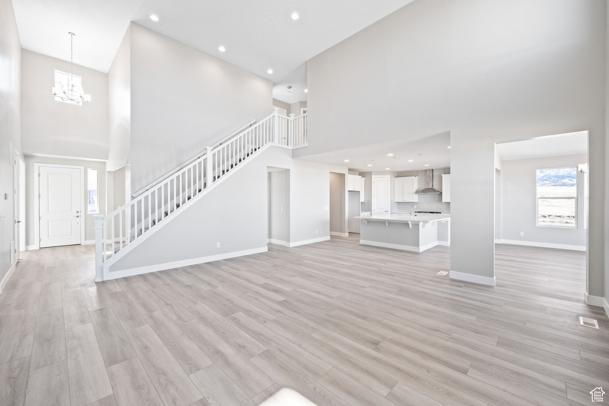 Unfurnished living room featuring light hardwood / wood-style flooring, a towering ceiling, and a chandelier