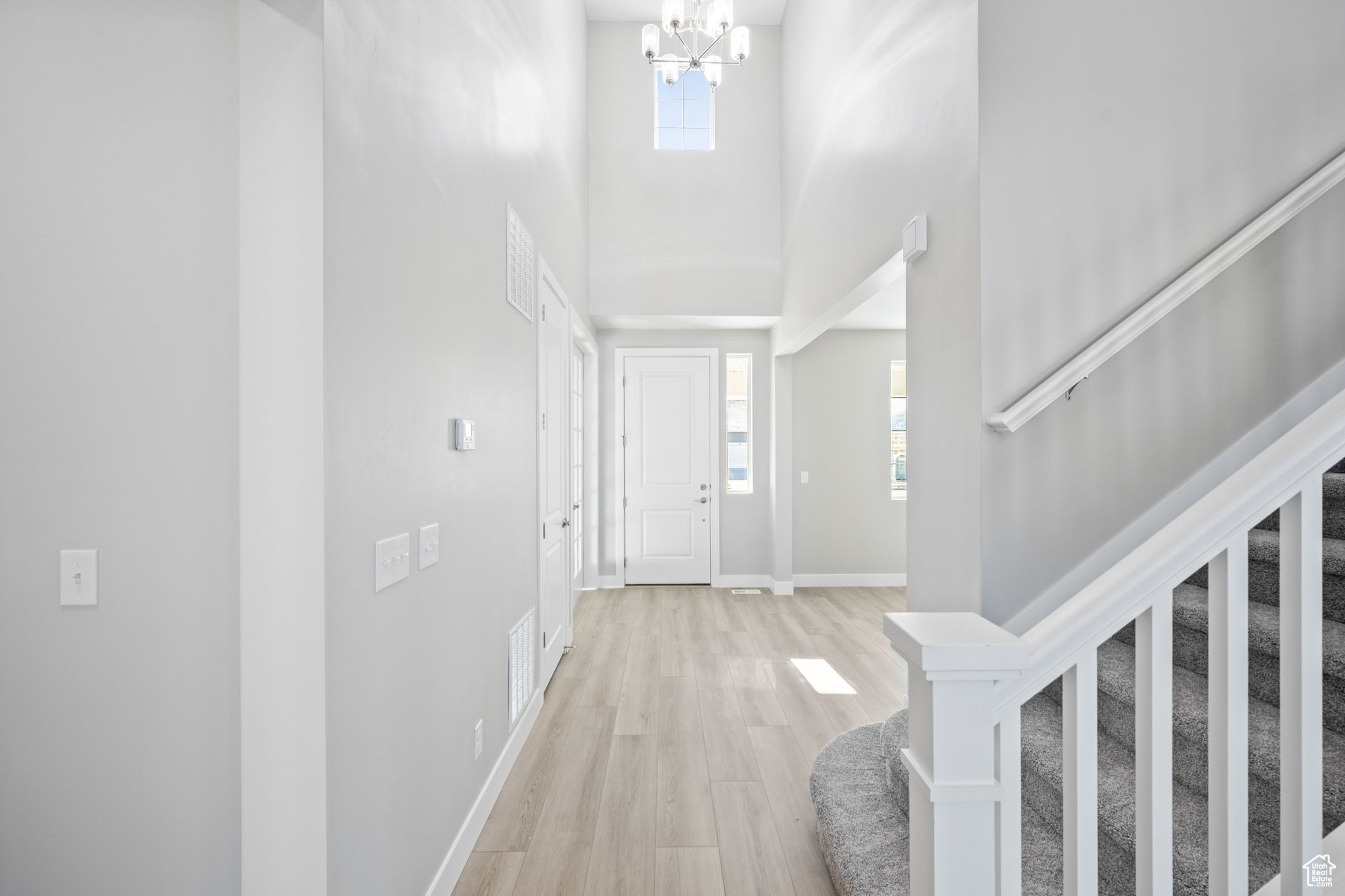 Foyer featuring light hardwood / wood-style flooring, a towering ceiling, and a chandelier