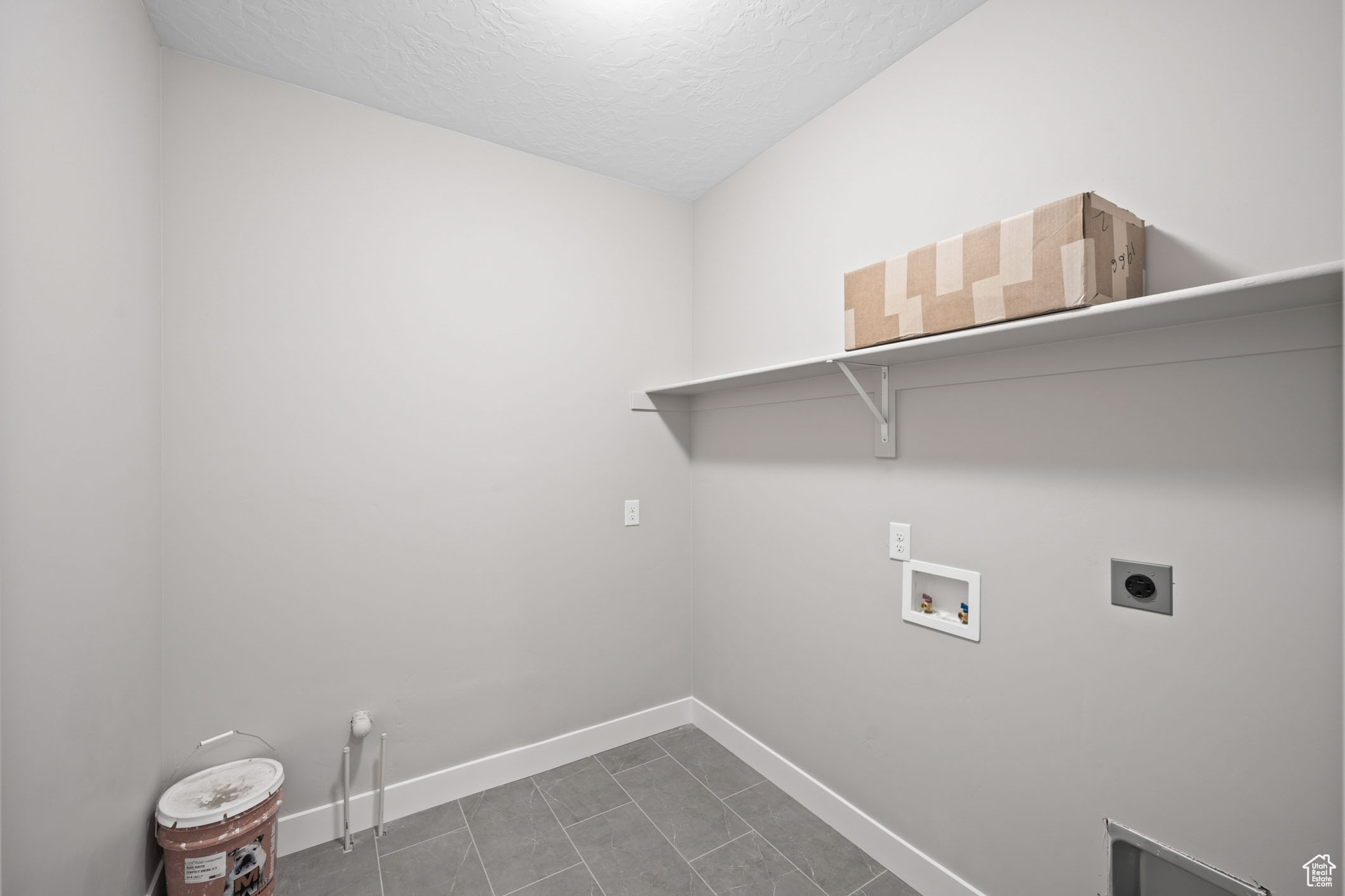 Washroom featuring hookup for an electric dryer, hookup for a washing machine, and a textured ceiling