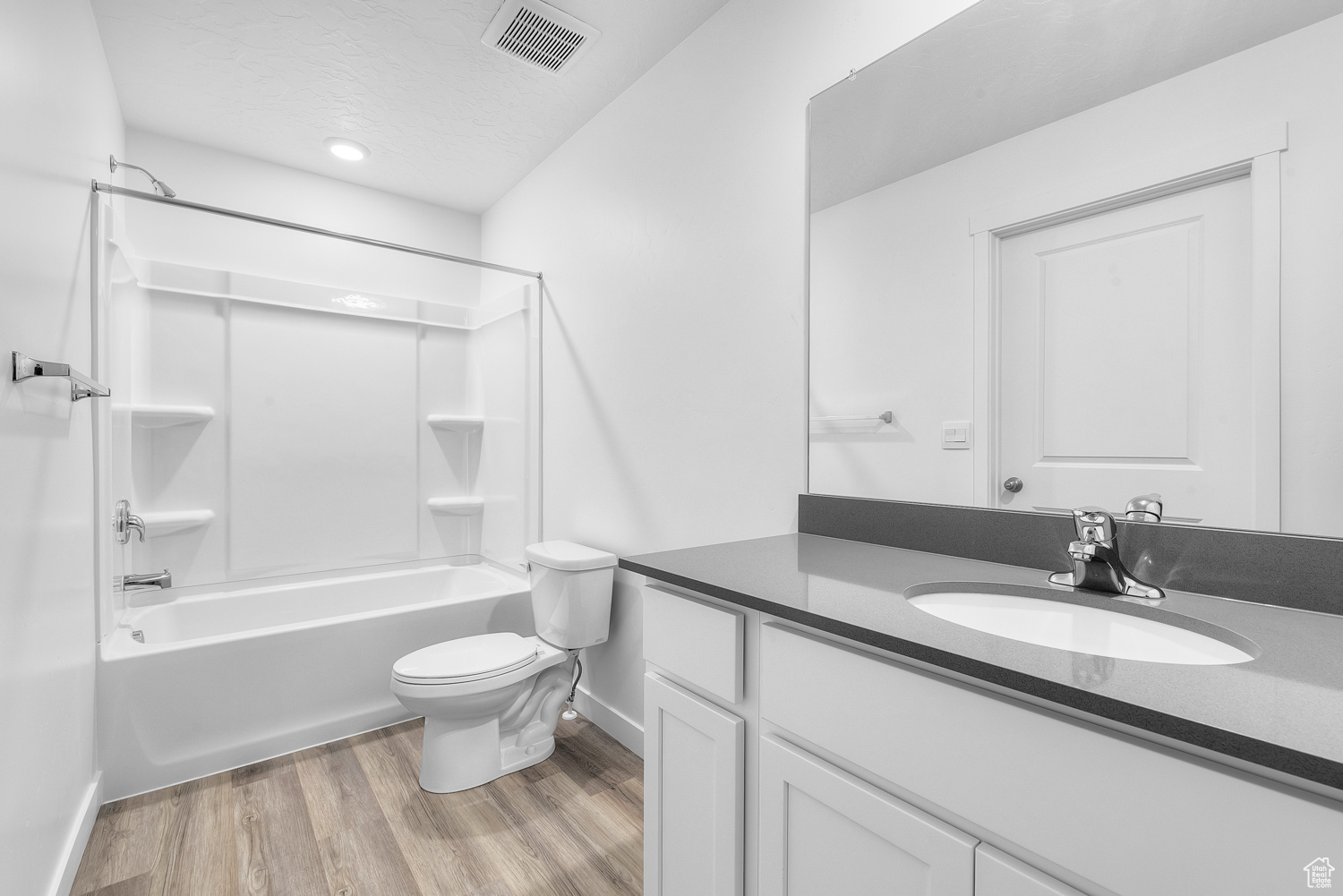 Full bathroom with vanity, bathing tub / shower combination, hardwood / wood-style flooring, toilet, and a textured ceiling