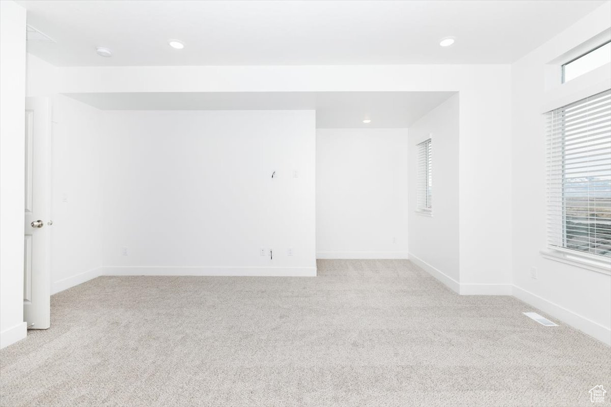 Unfurnished room featuring a healthy amount of sunlight and light colored carpet