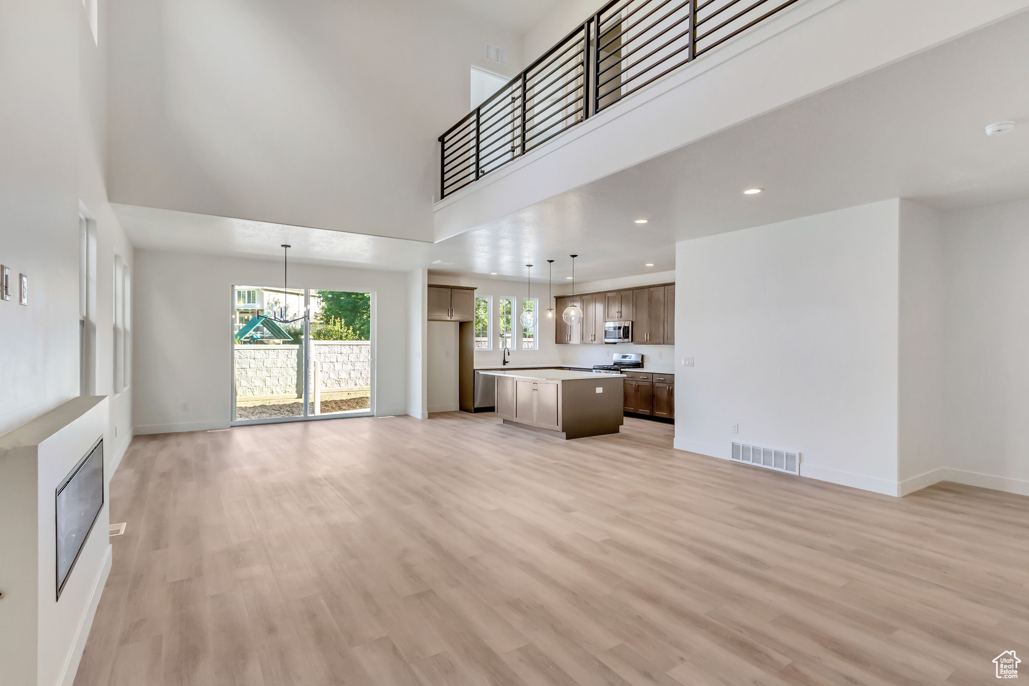 Unfurnished living room featuring light hardwood / wood-style floors, a high ceiling, and an inviting chandelier