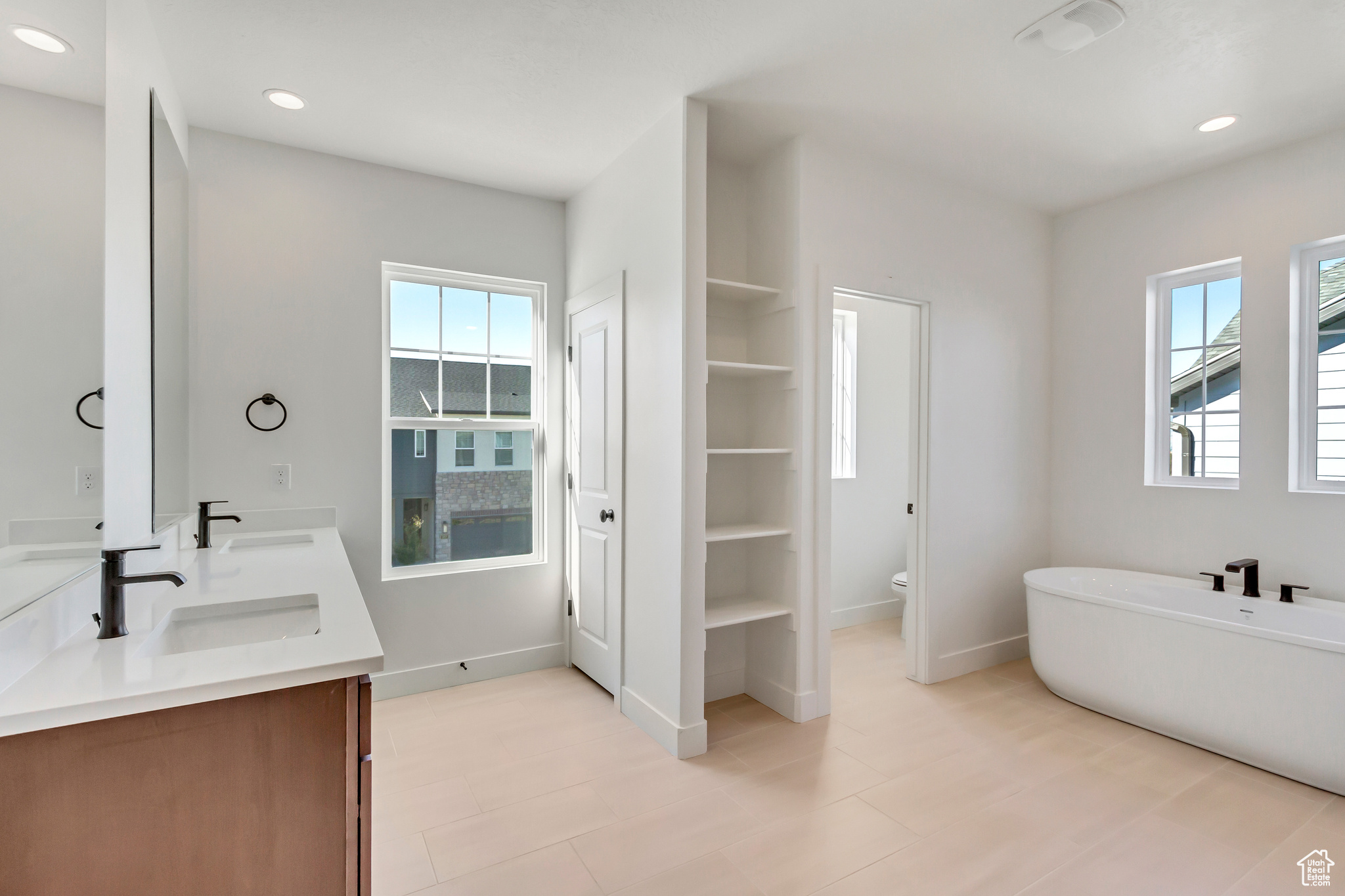 Bathroom featuring a washtub, vanity, and toilet