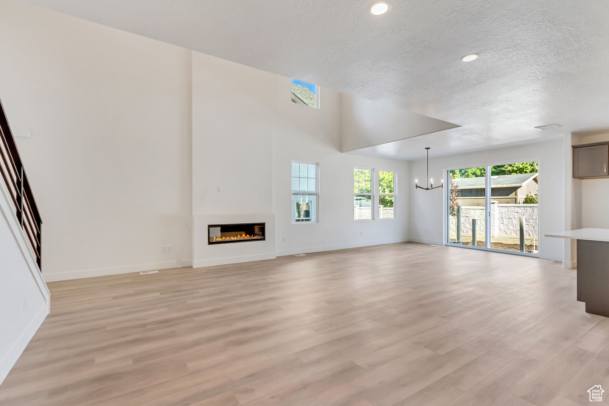 Unfurnished living room featuring light hardwood / wood-style floors, a textured ceiling, and an inviting chandelier