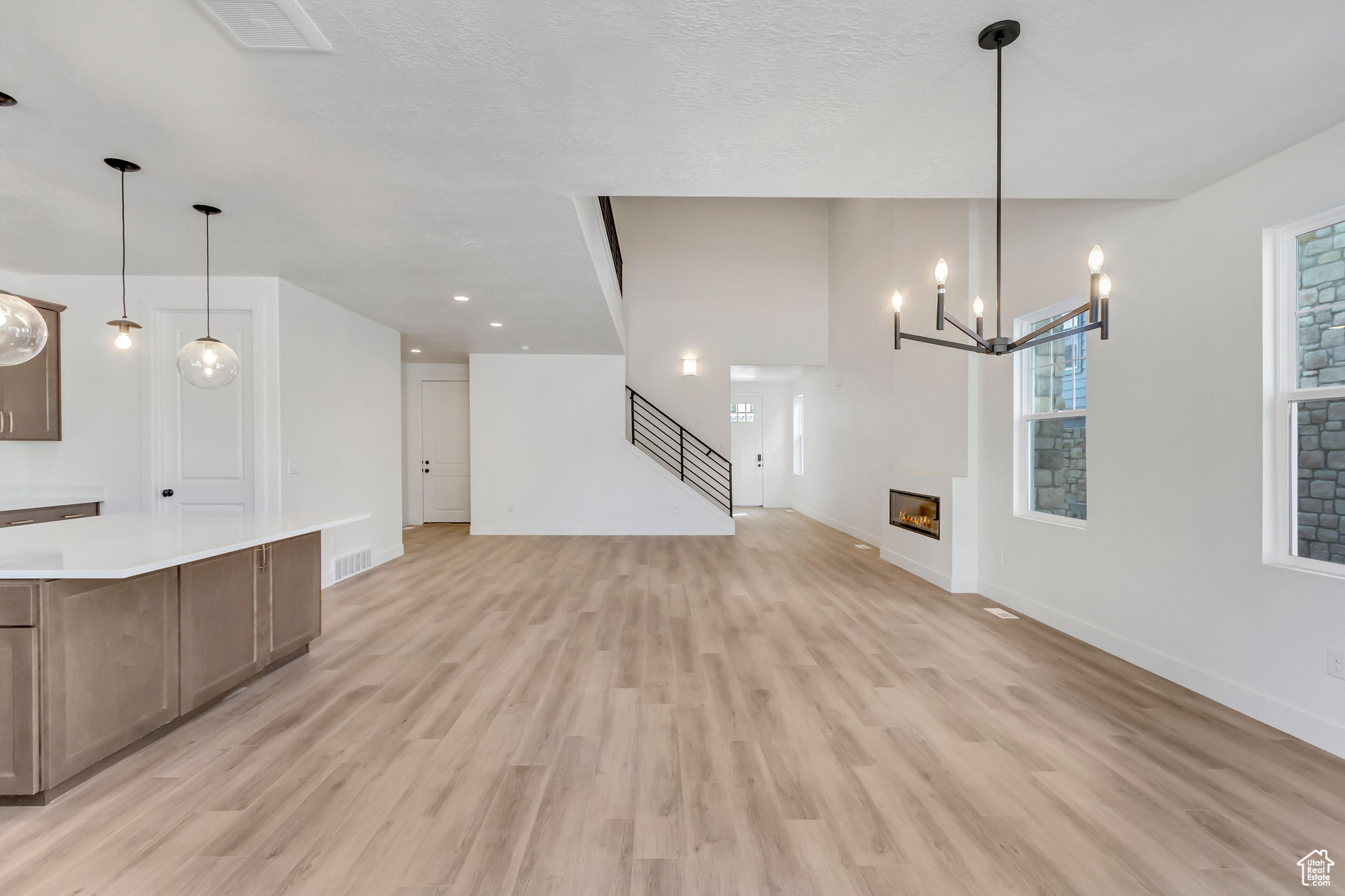 Unfurnished living room with a notable chandelier and light wood-type flooring