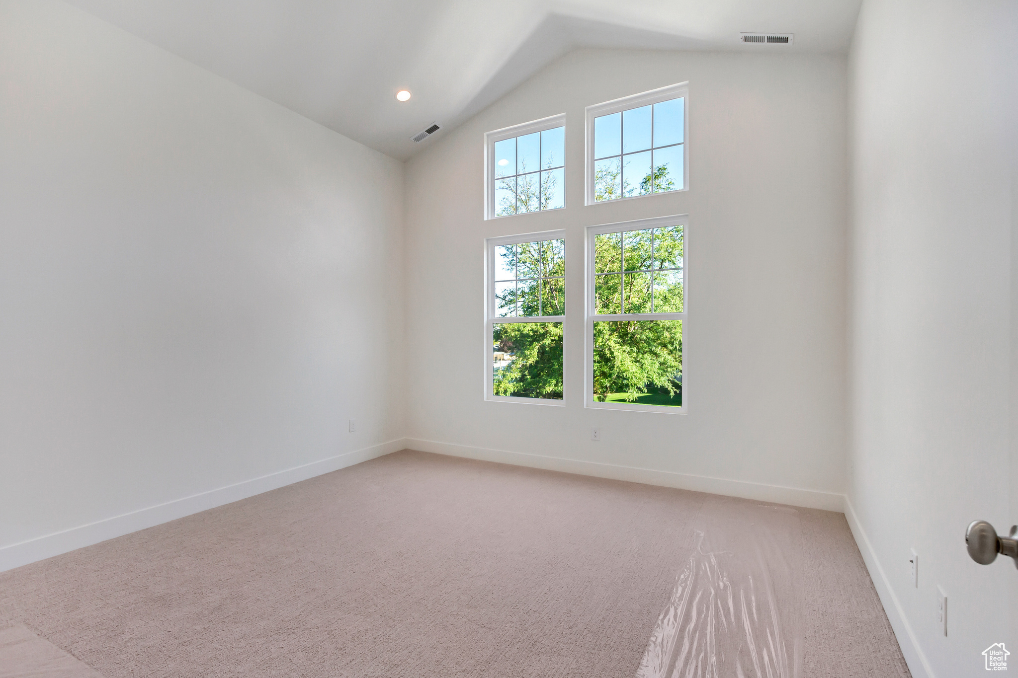 Carpeted empty room with vaulted ceiling