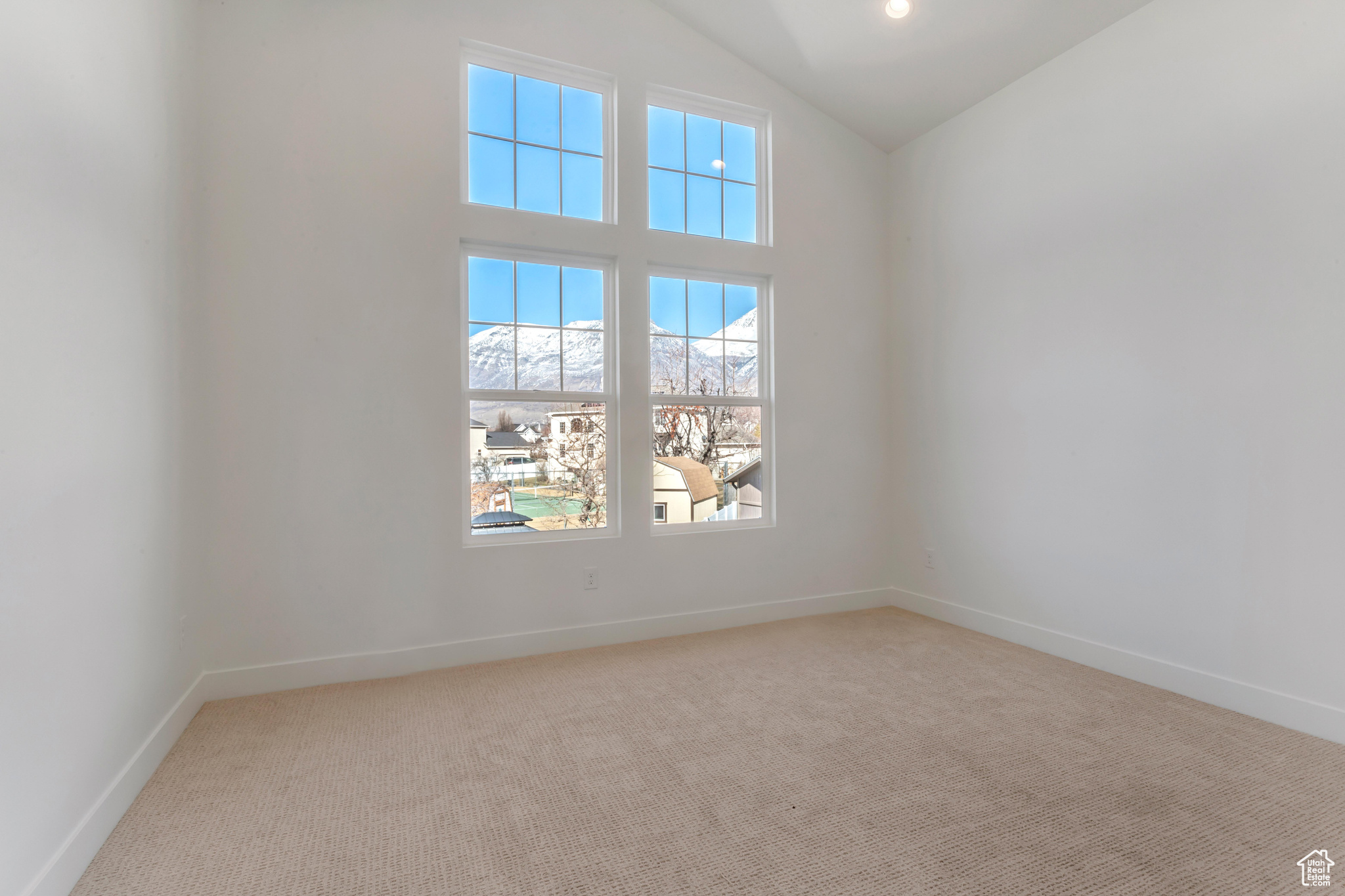 Unfurnished room with light carpet, a mountain view, and lofted ceiling