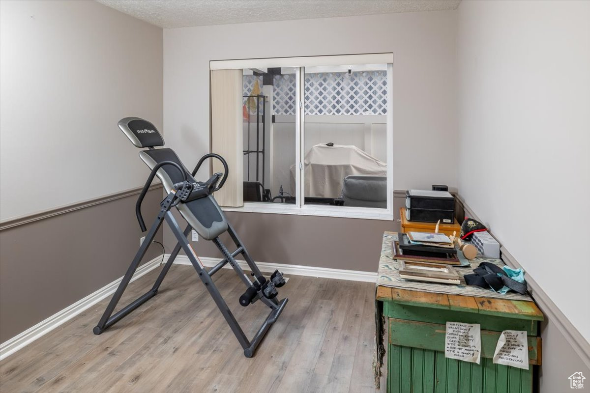 Exercise area featuring hardwood / wood-style floors and a textured ceiling