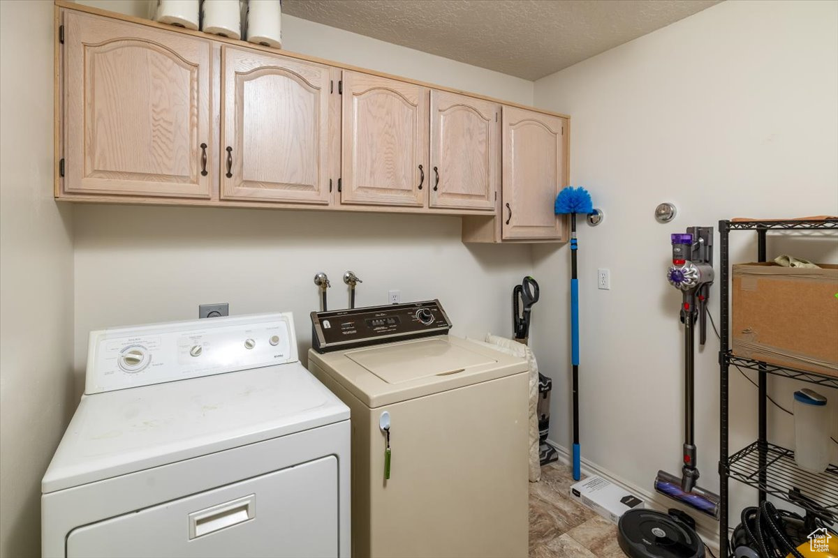 Laundry room with cabinets, independent washer and dryer, and a textured ceiling