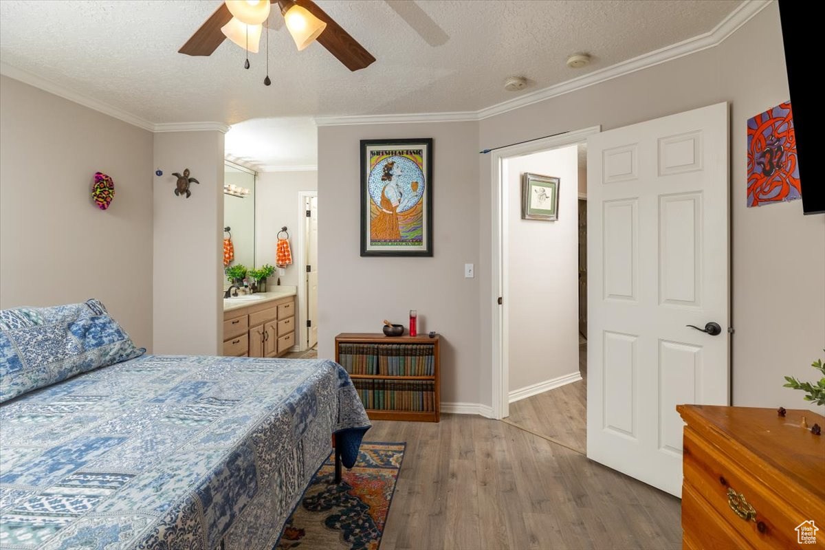 Bedroom with a textured ceiling, hardwood / wood-style flooring, ensuite bath, and ceiling fan